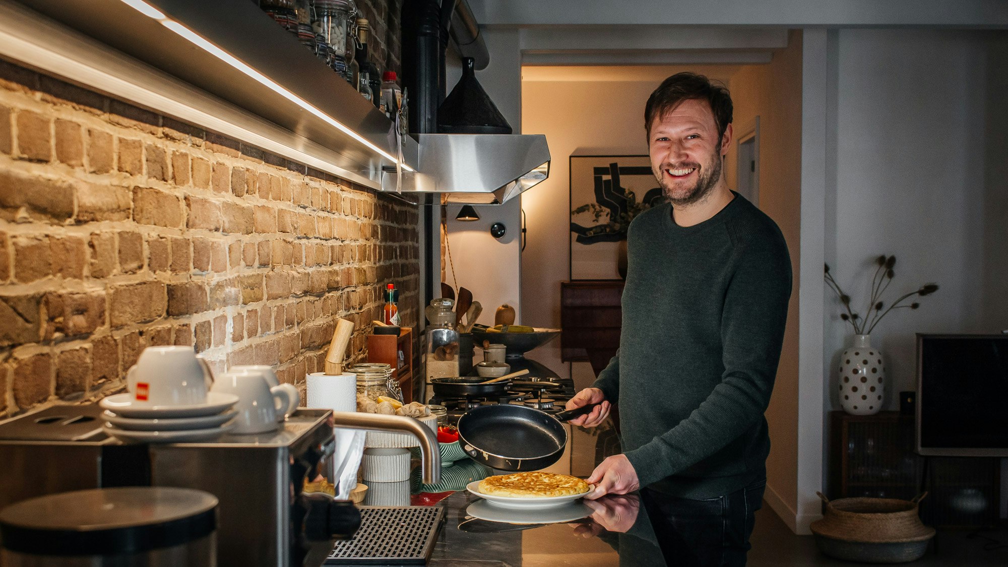 Diego hält eine Pfanne und kocht in einer Küche