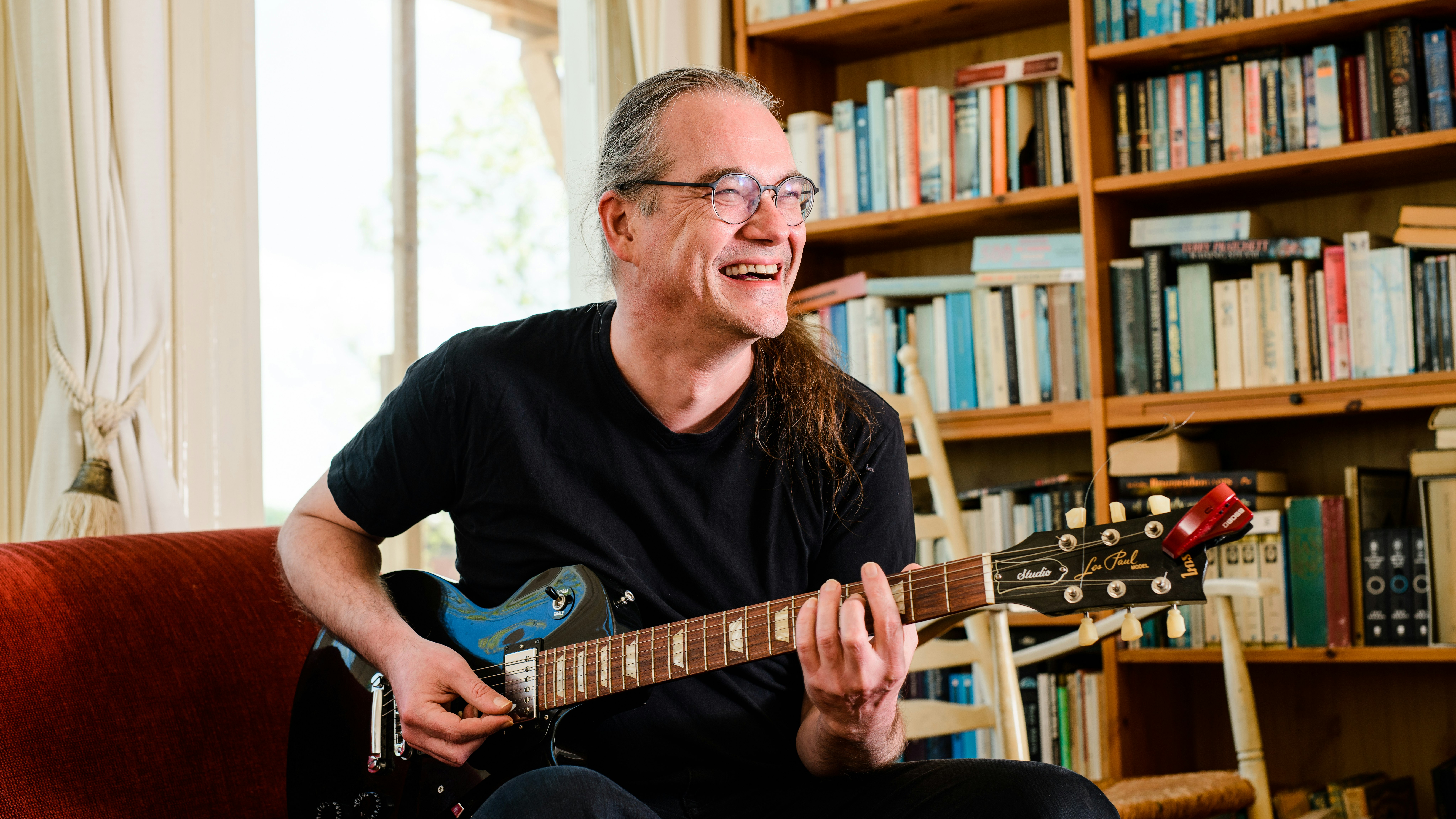 Edwin enjoying his hobby, playing the electric guitar, at home.