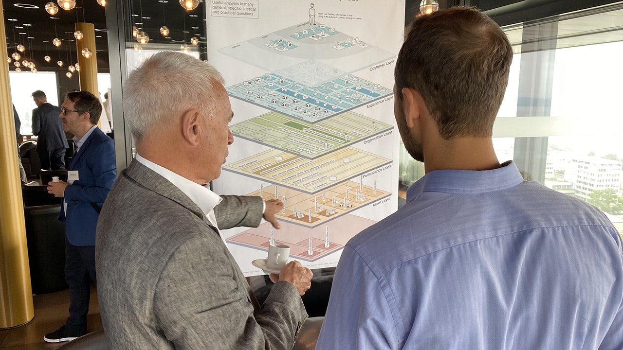 Two people looking at a poster showing the exploded view