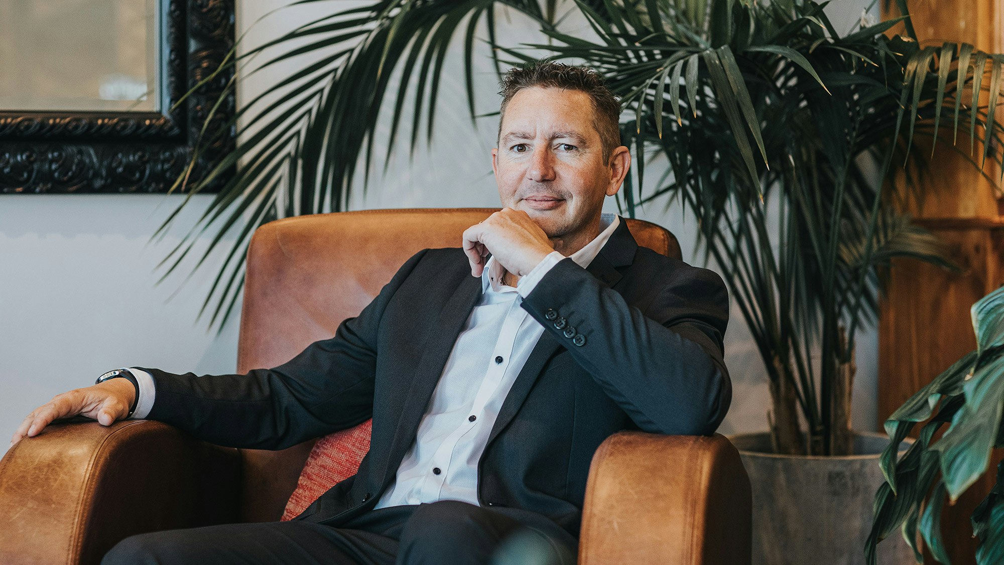 Mick in suit sitting on a leather chair