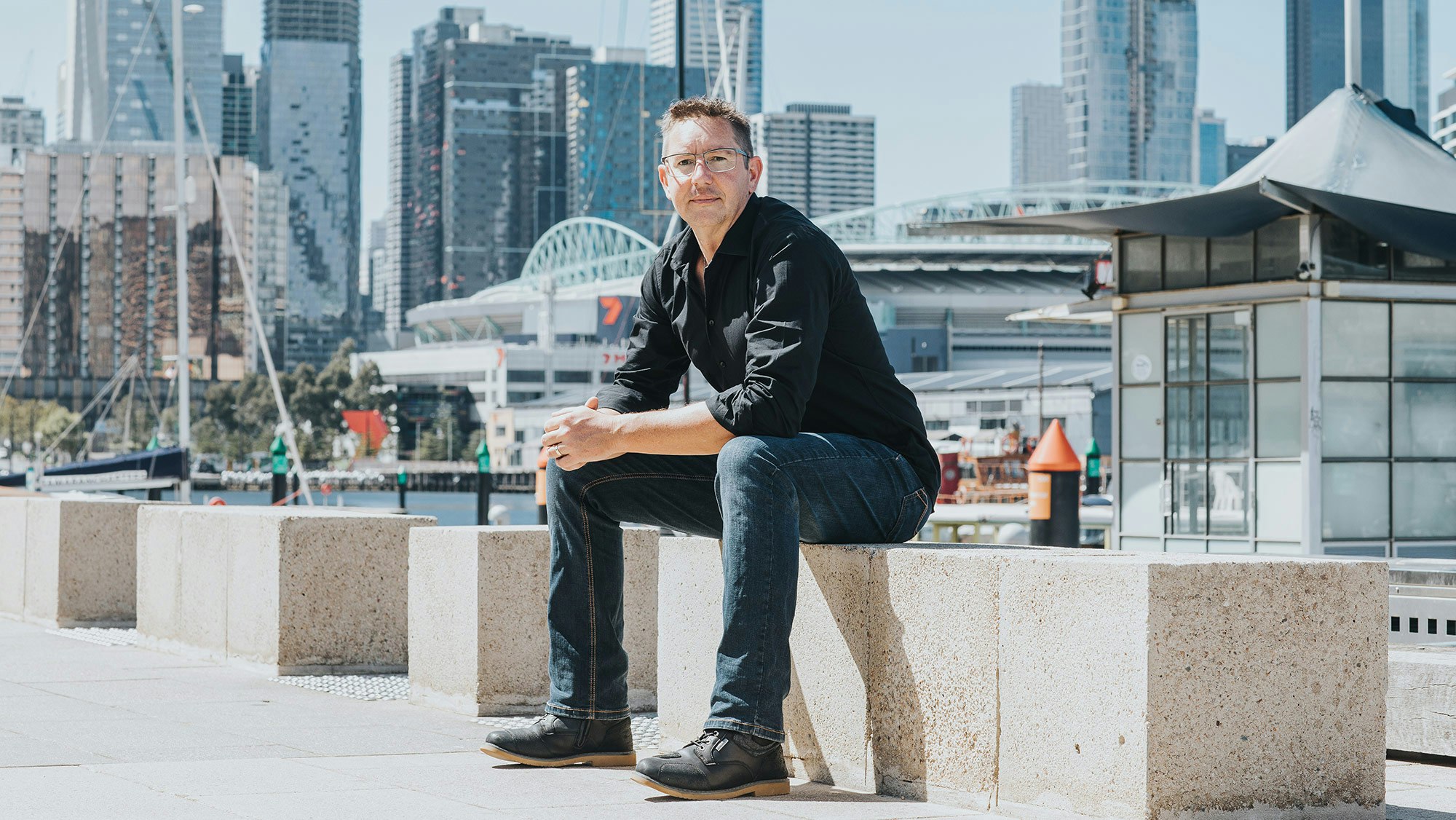 Mich in shirt and jeans sitting at a harbour