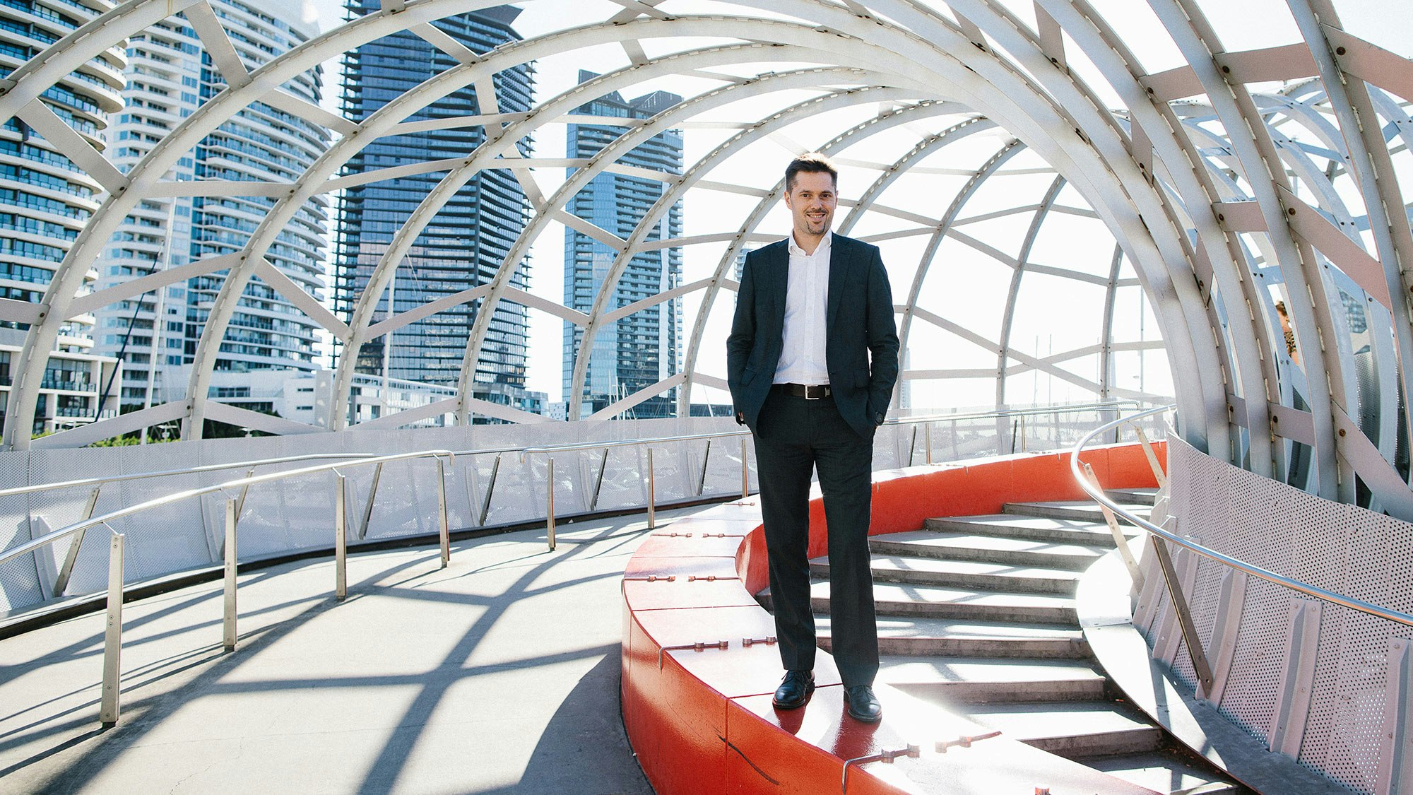 Bernard in a suit under an arch of a bridge