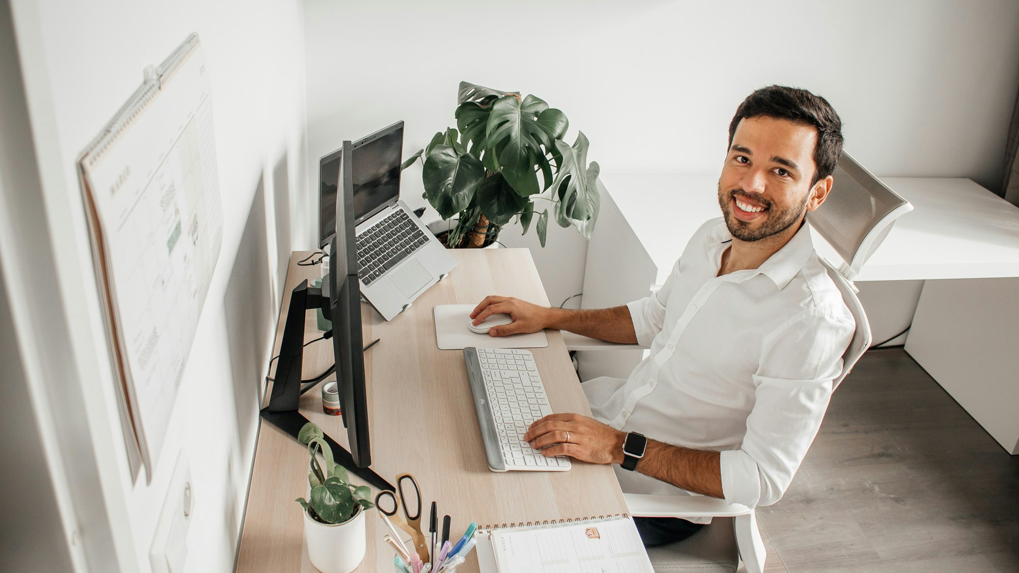 Felipe at a desk with a large screen and surrounded by plants