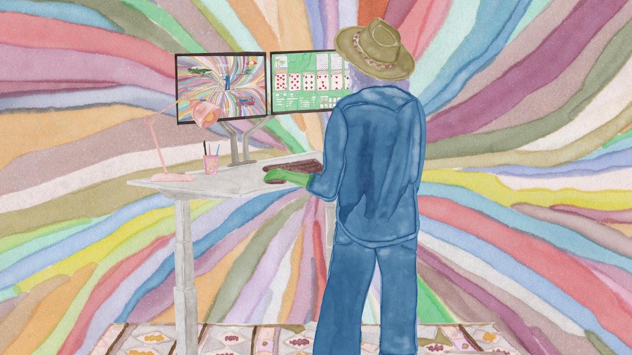 A person in a blue suit in front of two screens, surrounded by a lot of colours