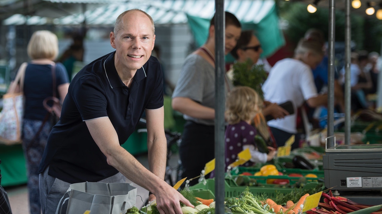 Christian Leeger picking a vegetables at a market