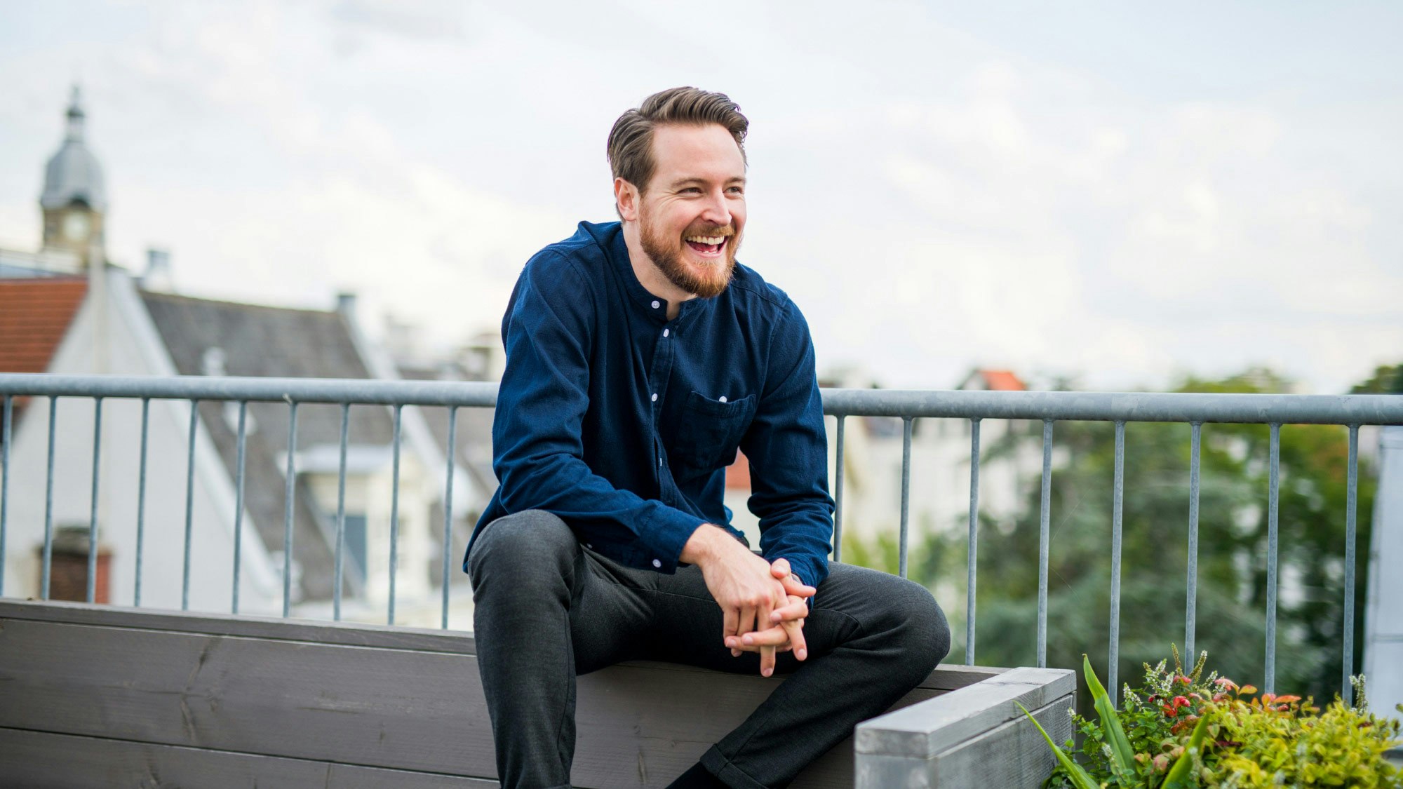 Kevin Krifter laughing, sitting on a roof terrace bench.