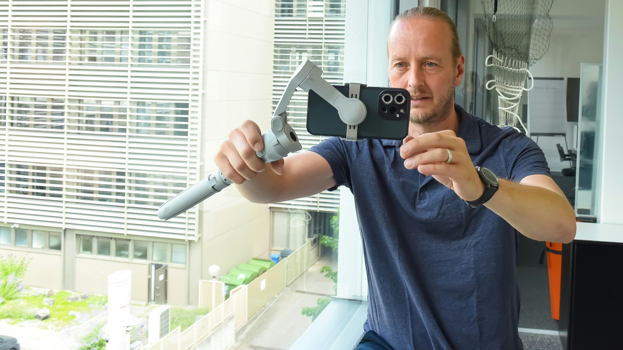 Hannes Benjamin Weikert recording a video on his phone with a video stick.