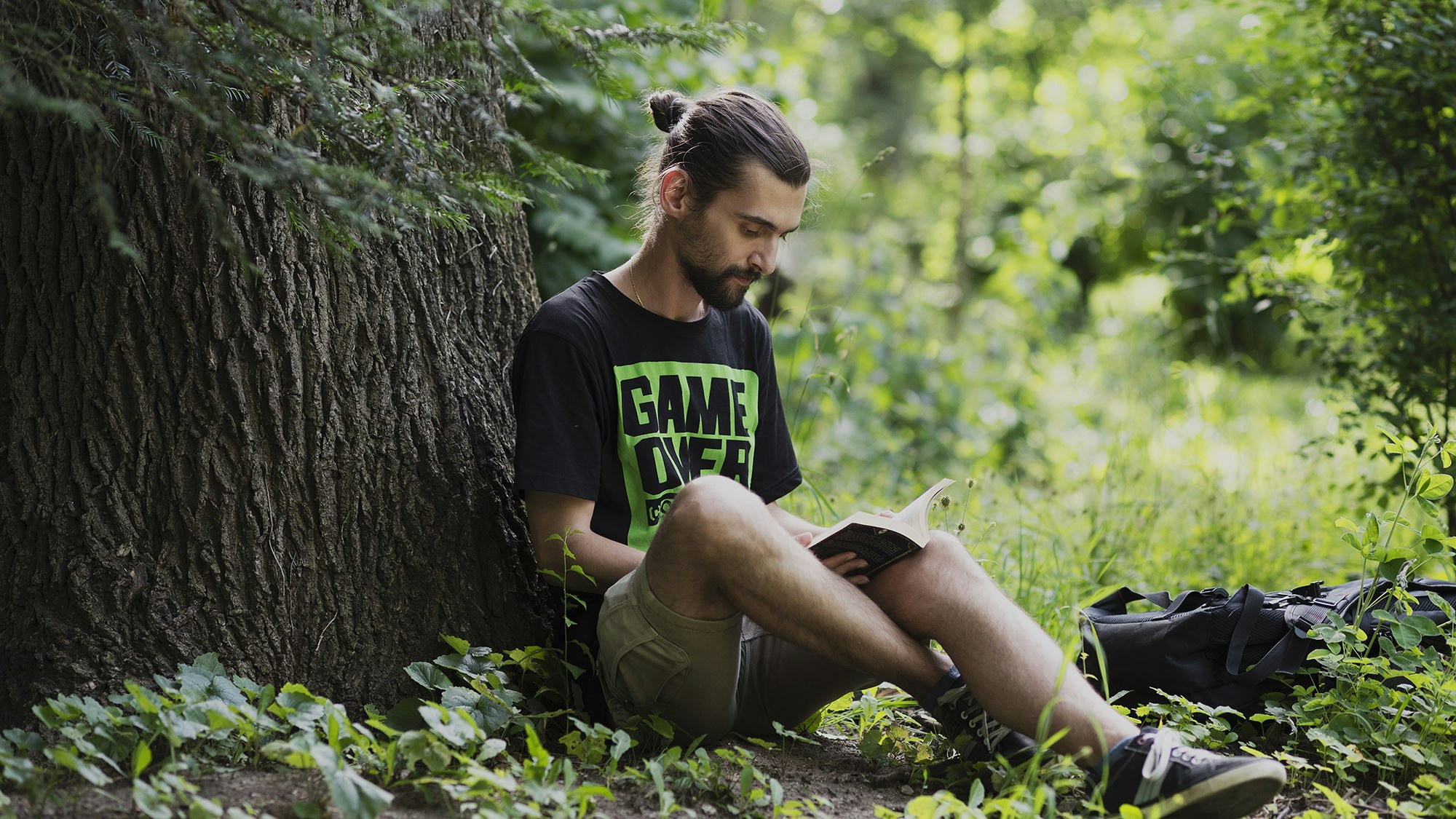 Ivan Kolarov reading a book in a forest.