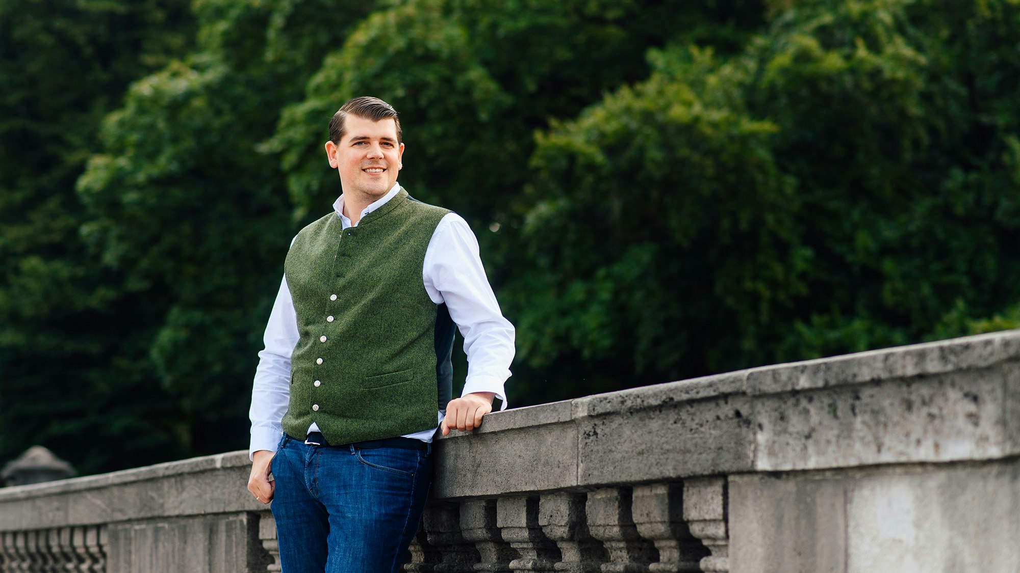 Jens Plattfaut on a stone bridge with dark green trees in the background.