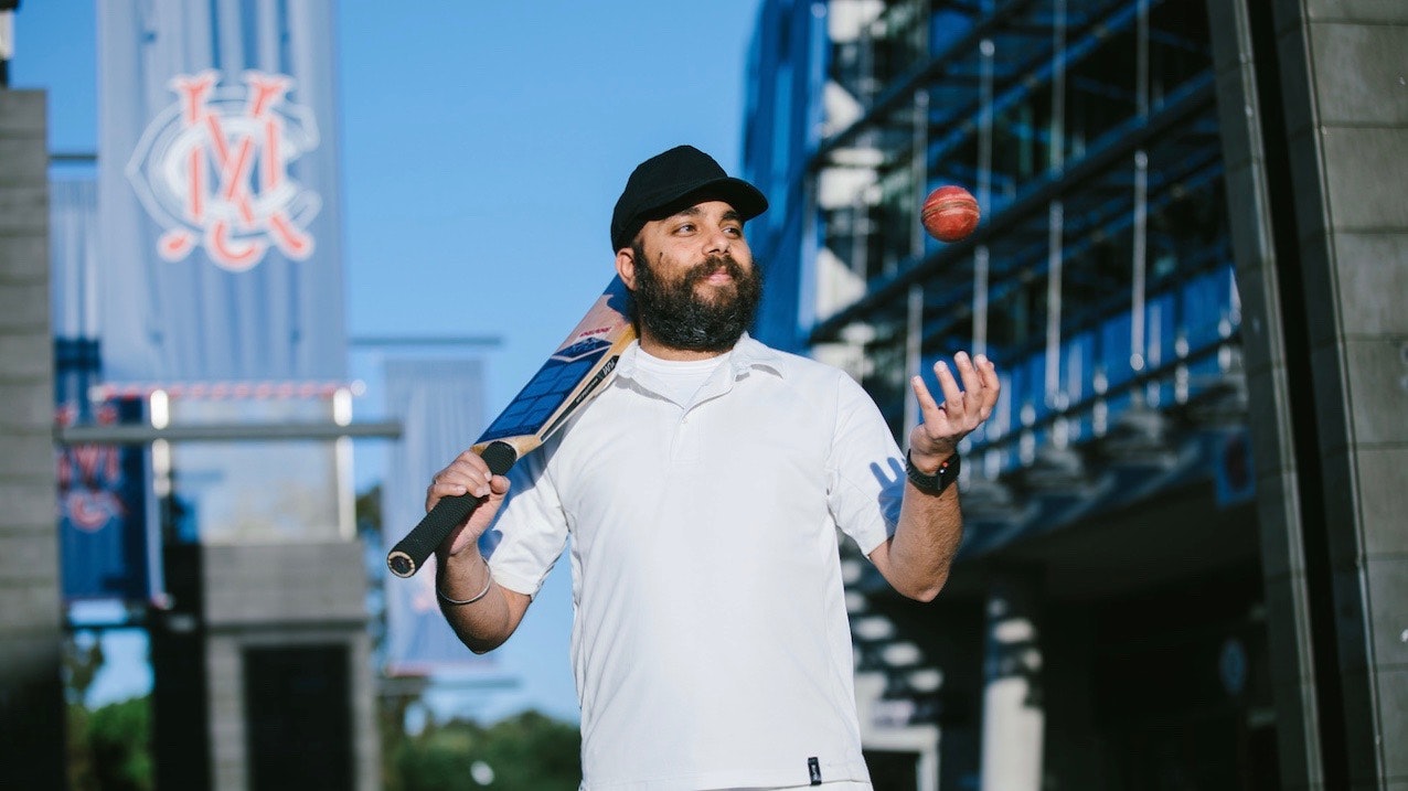 Randeep Gandhi focused in a cricket ball, with cricket bat over his shoulder.