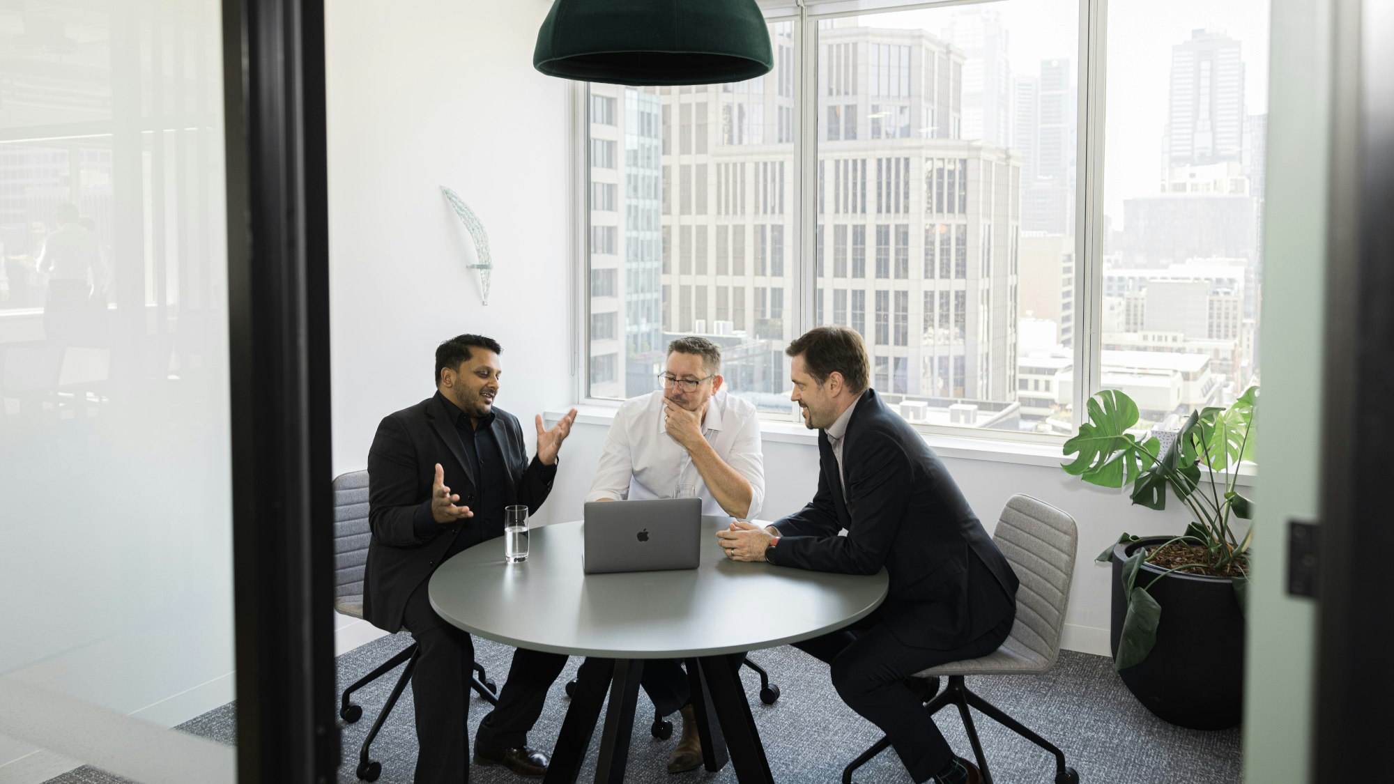 Three employees sit together at the round table.