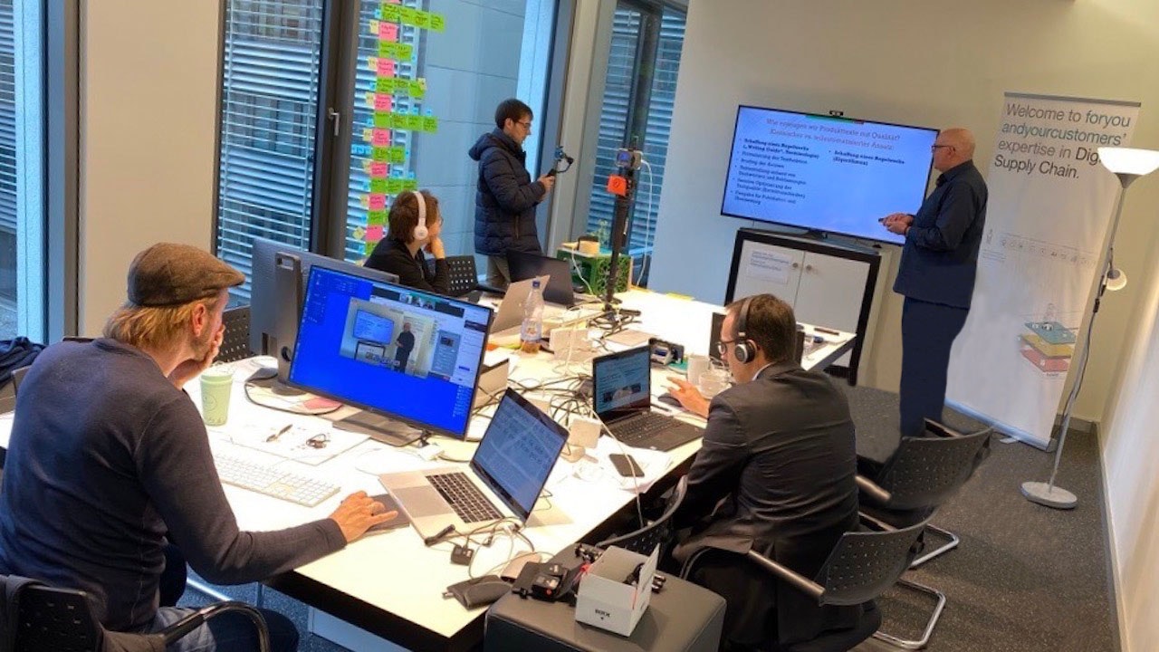 5 people in a room surrounded by laptops, computers and screens