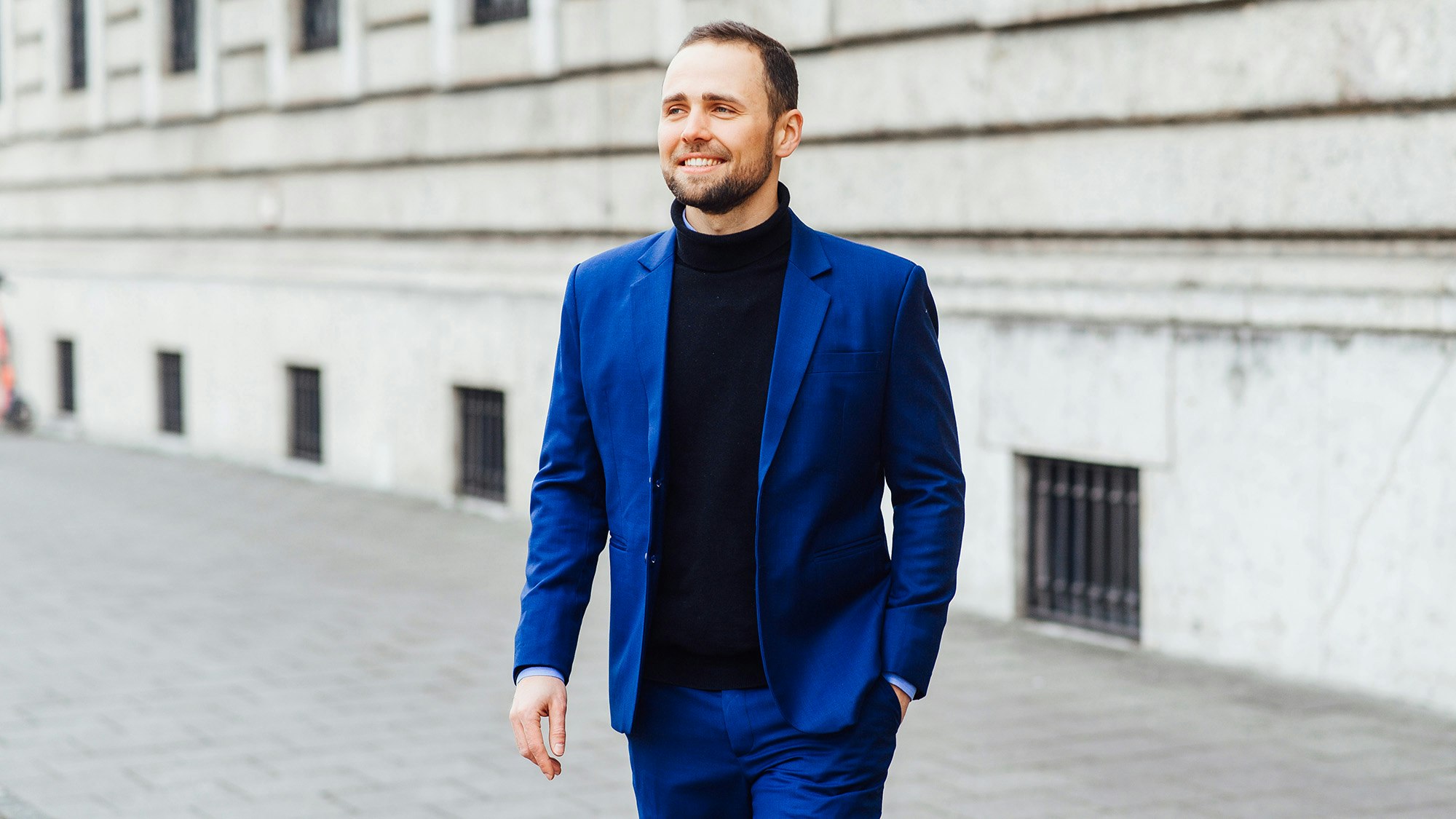 Tobias Bartsch walking on a street in his suit with one hand in a pocket.