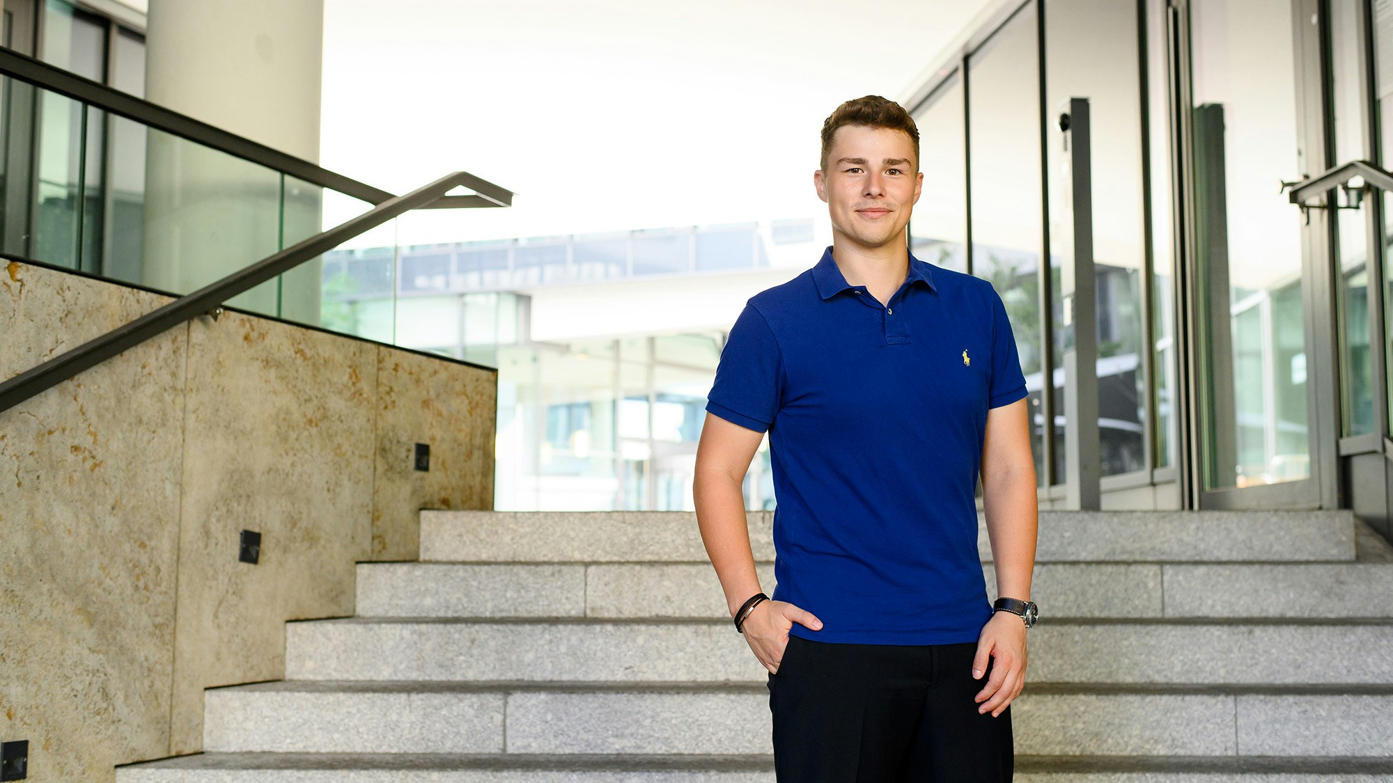 Arne Kupfer in a blue polo shirt, outside on a staircase of an office building.