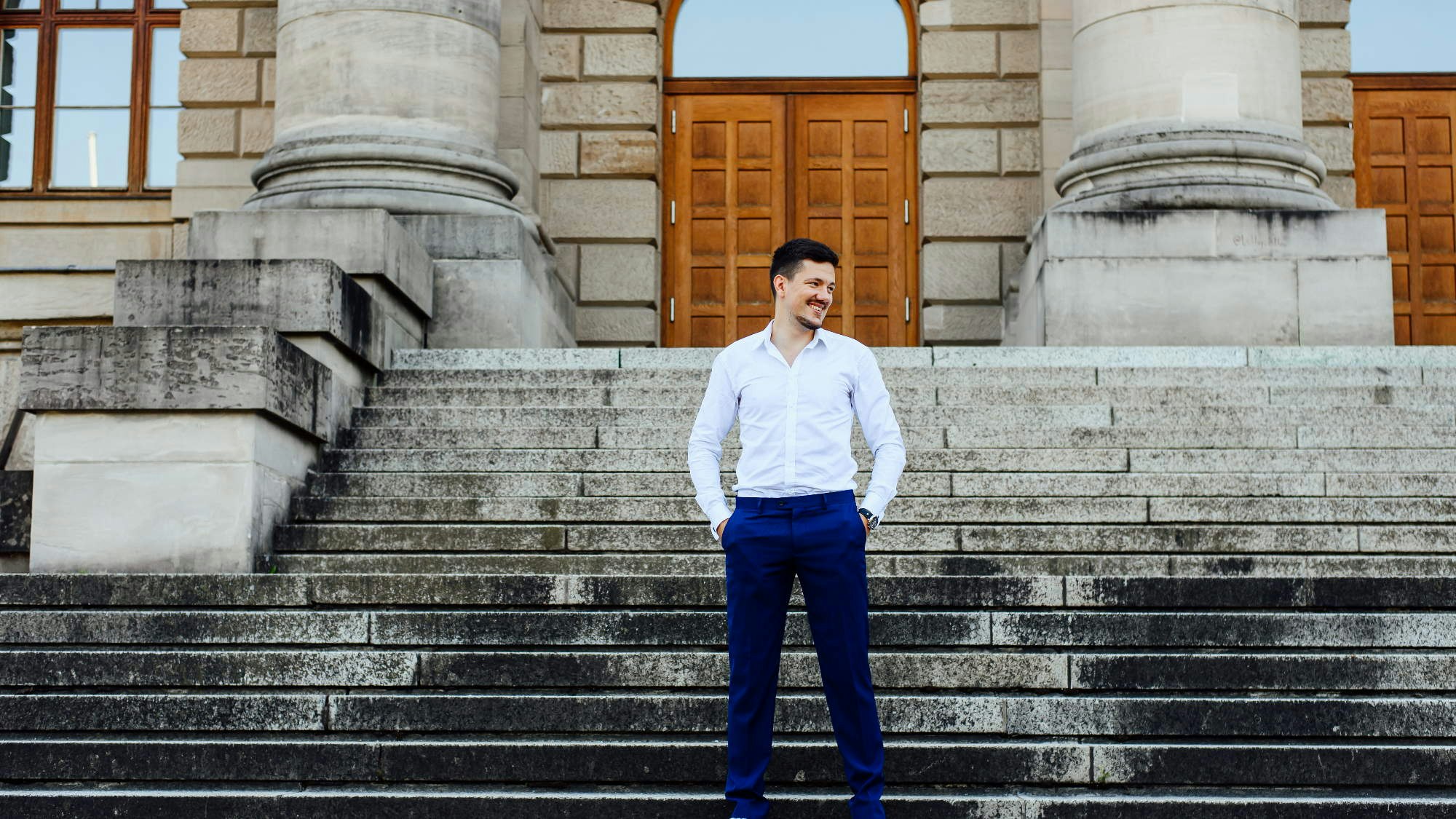 Michael Krawczyk in white shirt and blue formal pants standing at a stone staircase.