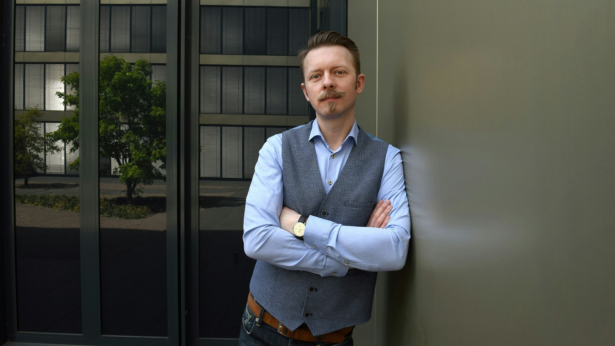 Damian Deßler in Hemd und schicker Weste. steht mit verschränkten Armen.