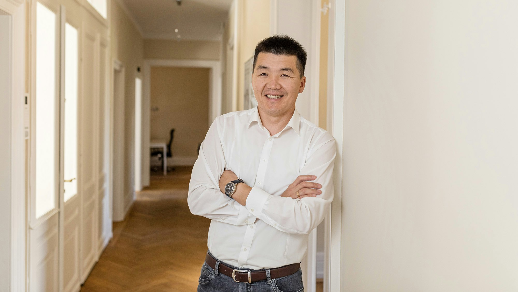 Tushig Tumenjargal is standing in an office hallway, arms crossed, looking into the camera.