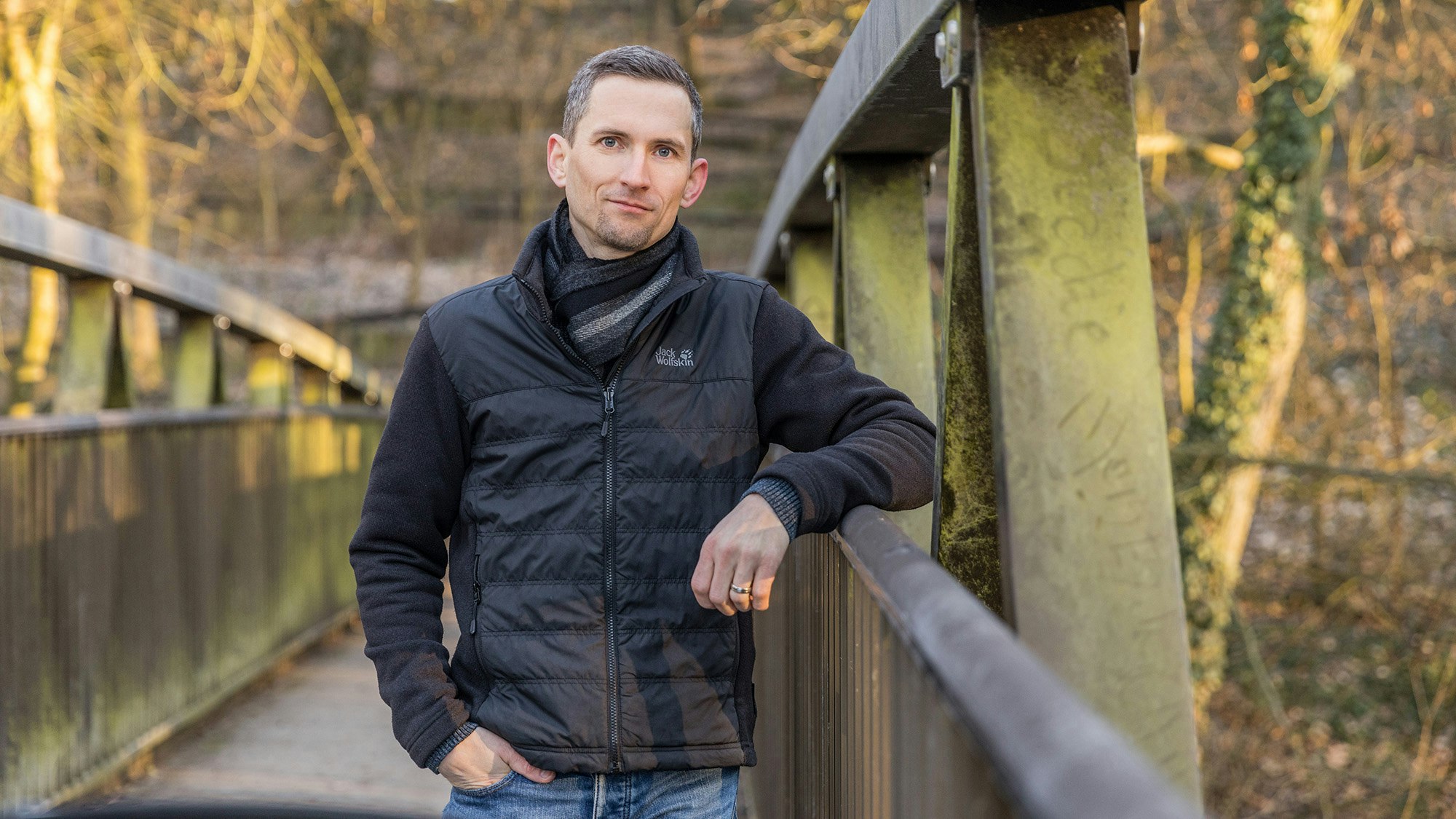 Christian Biller auf einer Brücke in der Natur, Blick in die Kamera.