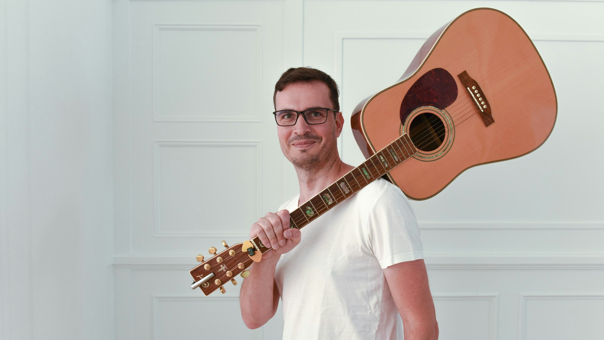 Christian Weih-Sum mit einer Gitarre über der Schulter.