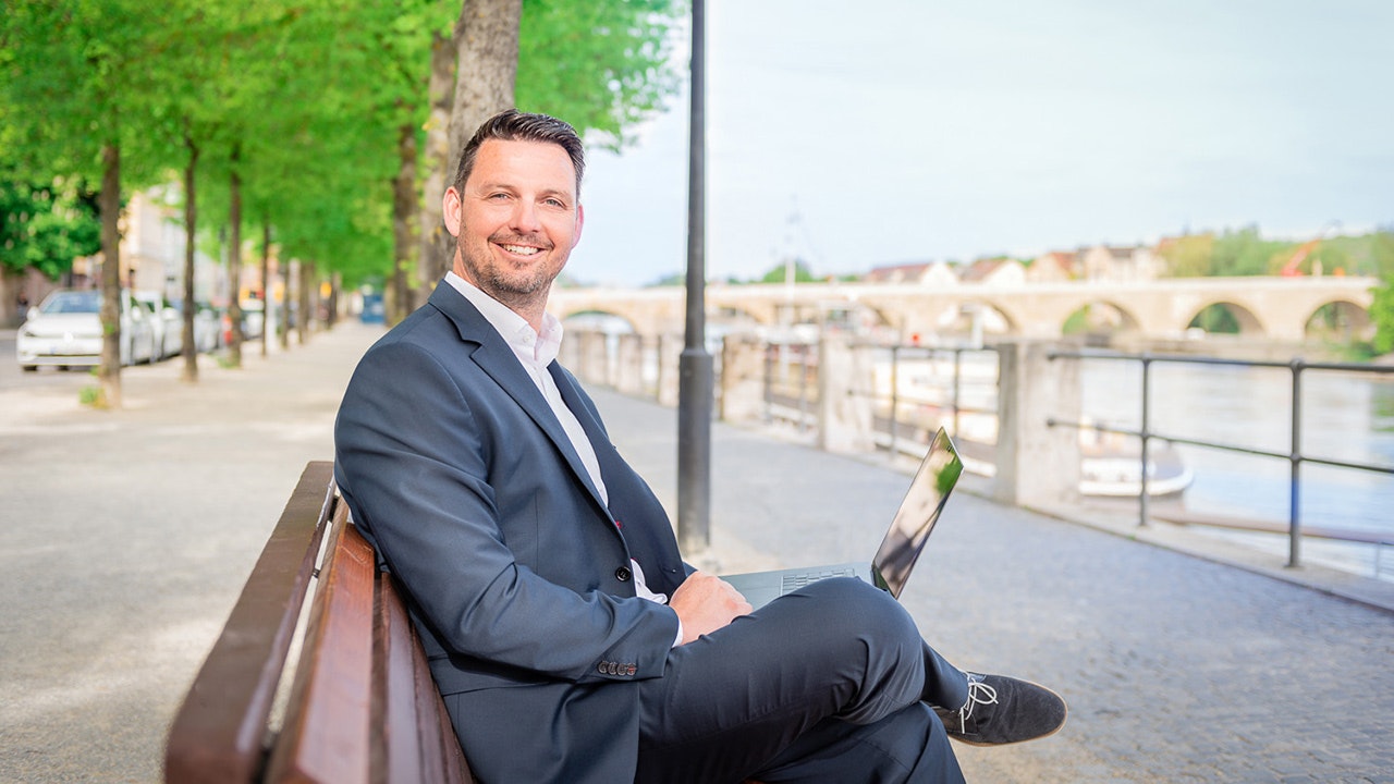 Andreas Breu sitting on a bench near the river.