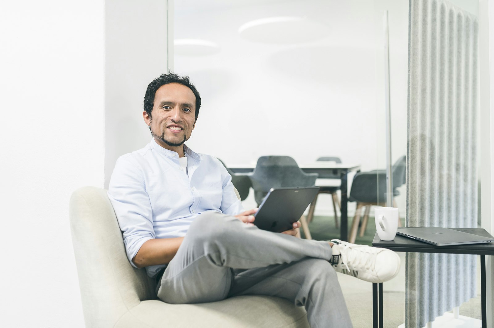 Jordan Hugo Abanto auf einer Couch in einem modernen Büro, das iPad in der Hand.