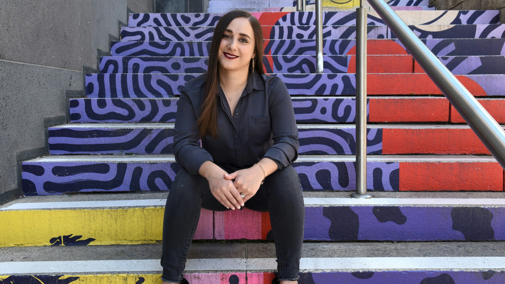 Valentina Zoffreo sitting on colourful, artsy stairs.