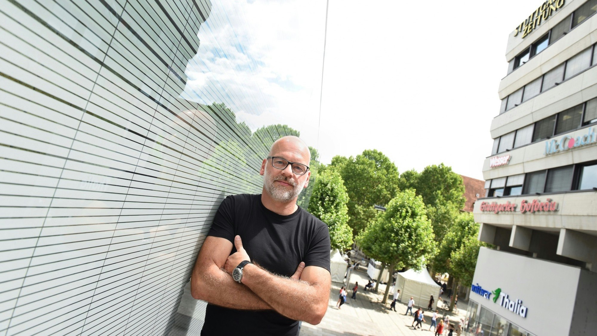 Rainer Fauth in a black t-shirt, standing with arms crossed on a street in Germany.