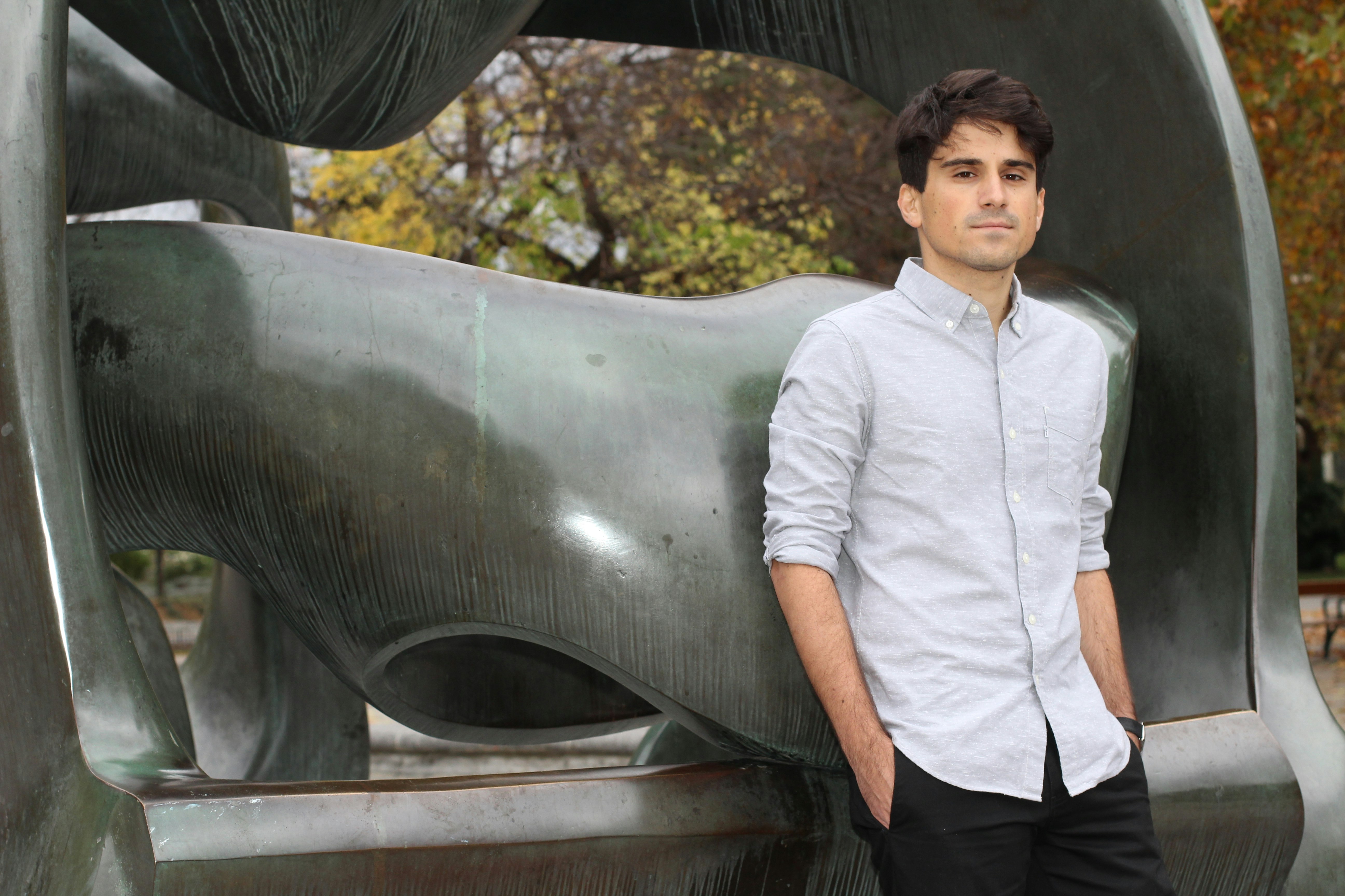 George with hands in pocket and leaning against a statue