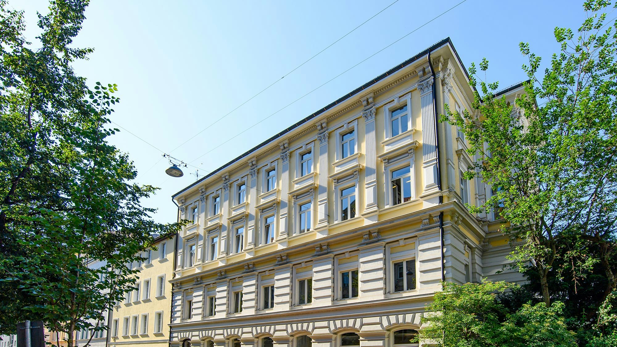 Die Außenansicht des neuen Büros ist zu sehen. Ein schöner Altbau mit einer lebhaften Fassade in Gelbtönen.