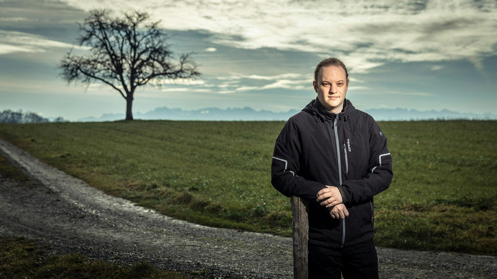 Yanneck leaning on a pole in the middle of a landscape