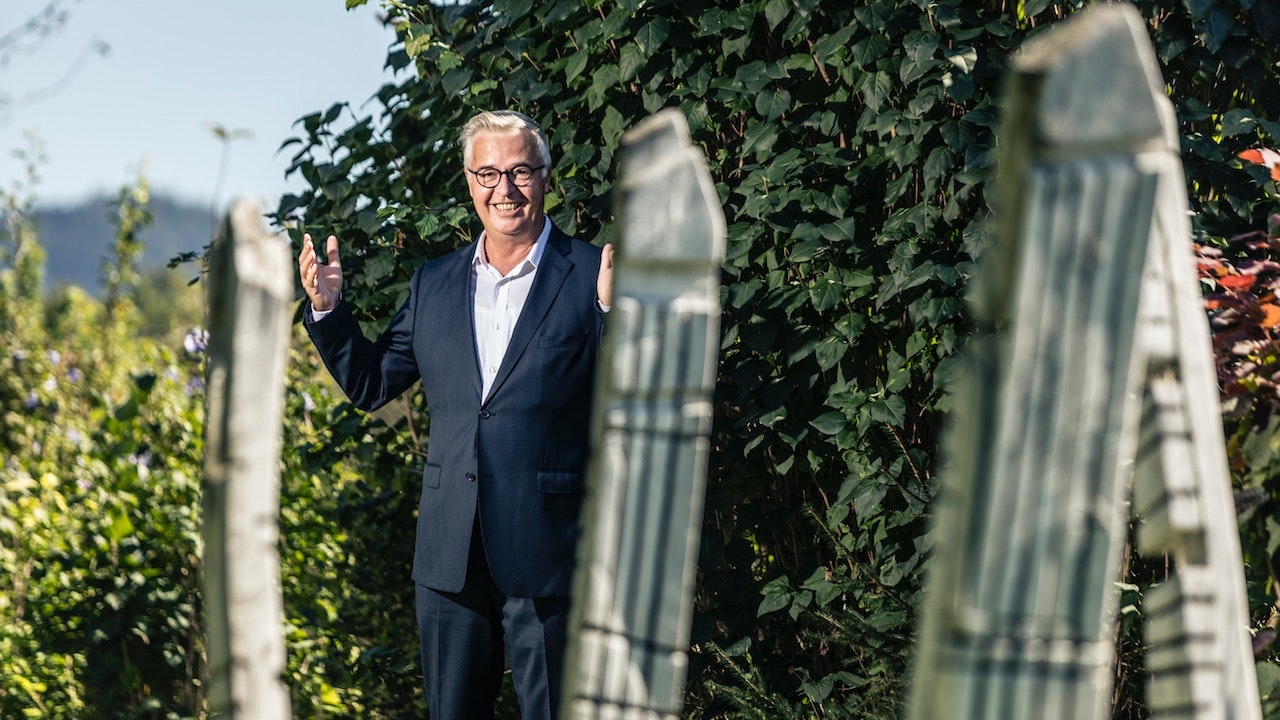 Robert Josef Stadler standing in a garden, slightly waving.