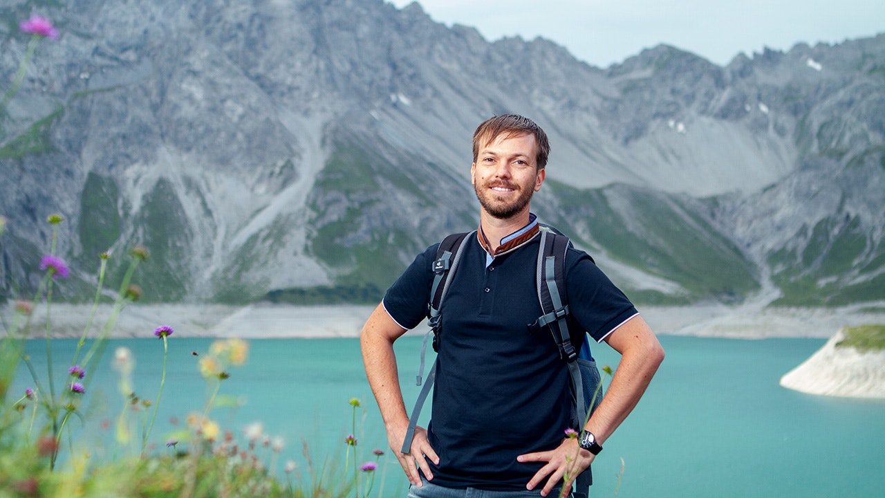 Christian steht in der Natur mit den Händen in der Seite
