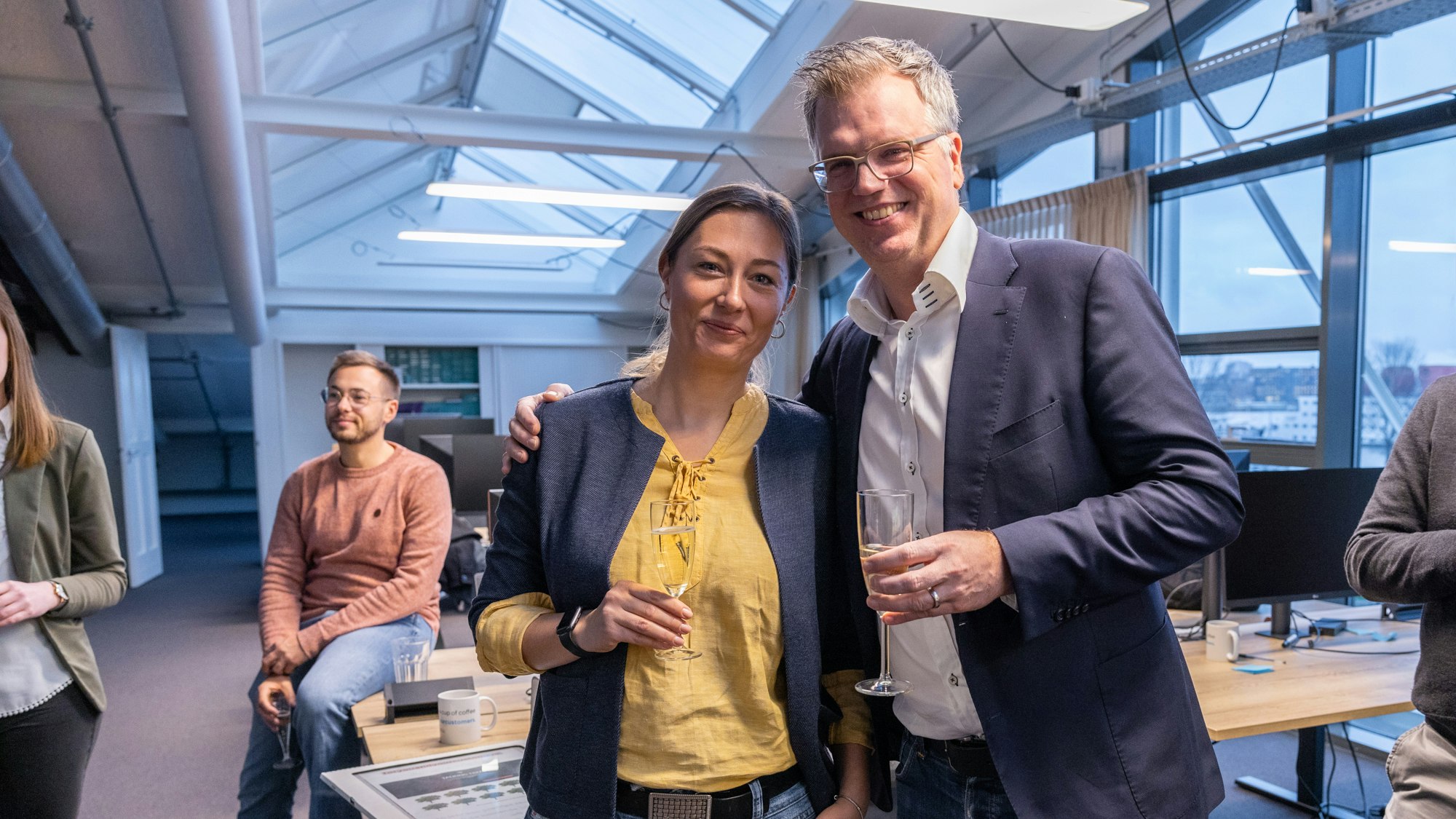 Jonathan Möeer in a dark suit and white shirt, together with Albena Mancheva in a yellow shirt and blue jacket, both smiling in the camera