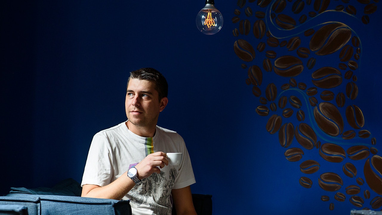 Nikolay sitting on a couch, holding a mug