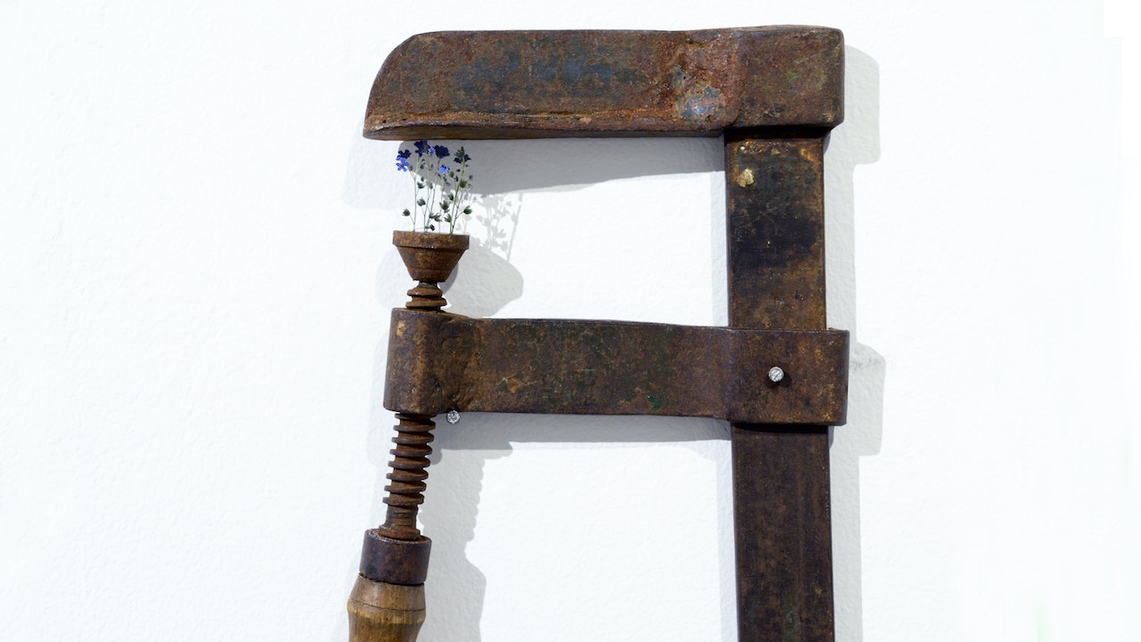 Image of a metal work tool turned into art with tiny blue flowers.