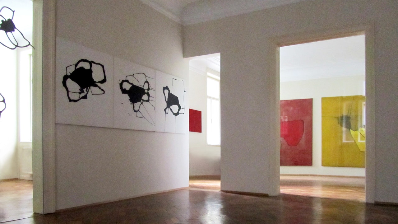 Kunst in einem Büro mit Galeriecharakter, der Schwerpunkt liegt auf drei abstrakten Formen, ähnlich einer verschütteten Tintenzeichnung, schwarz auf weißer Leinwand.