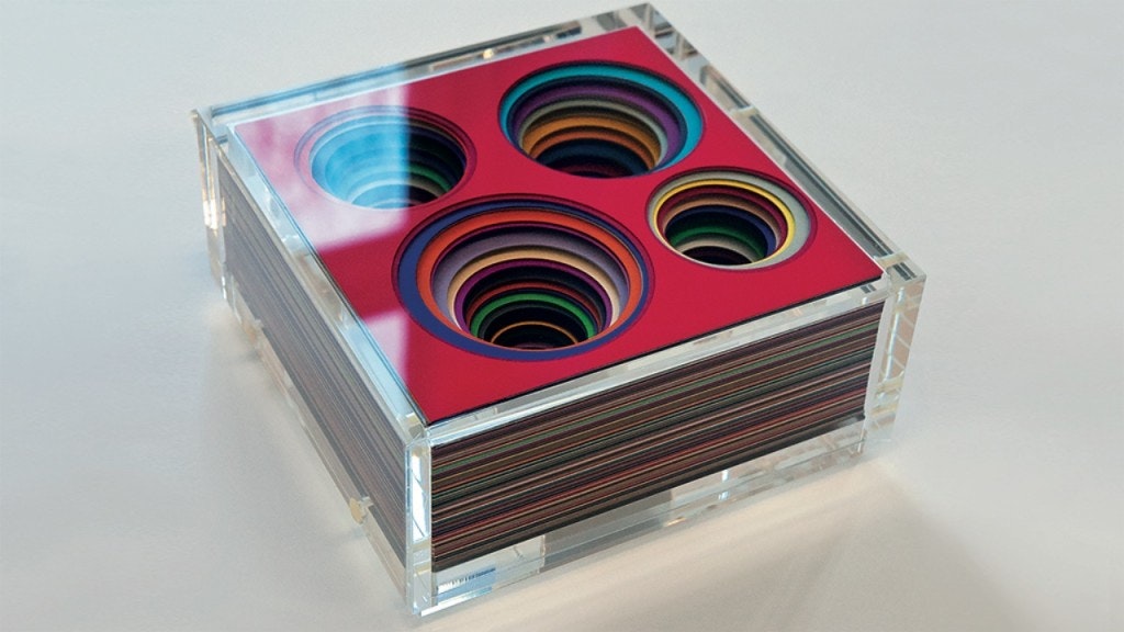 Eine durchsichtige Schachtel mit vielen Schichten, jede in einer anderen Farbe und jede mit vier Löchern.