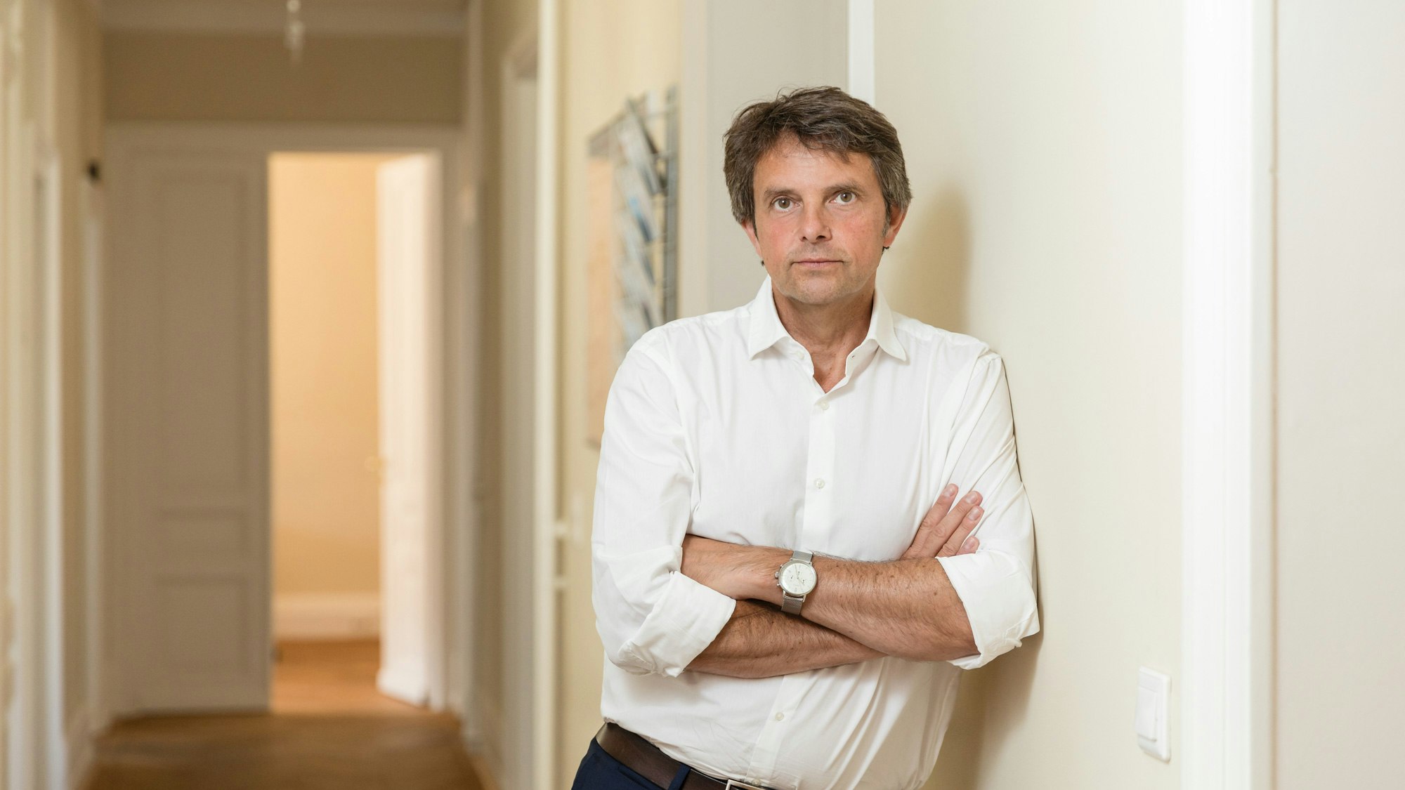 Werner Spengler standing in the hallway with arms crossed and a white shirt