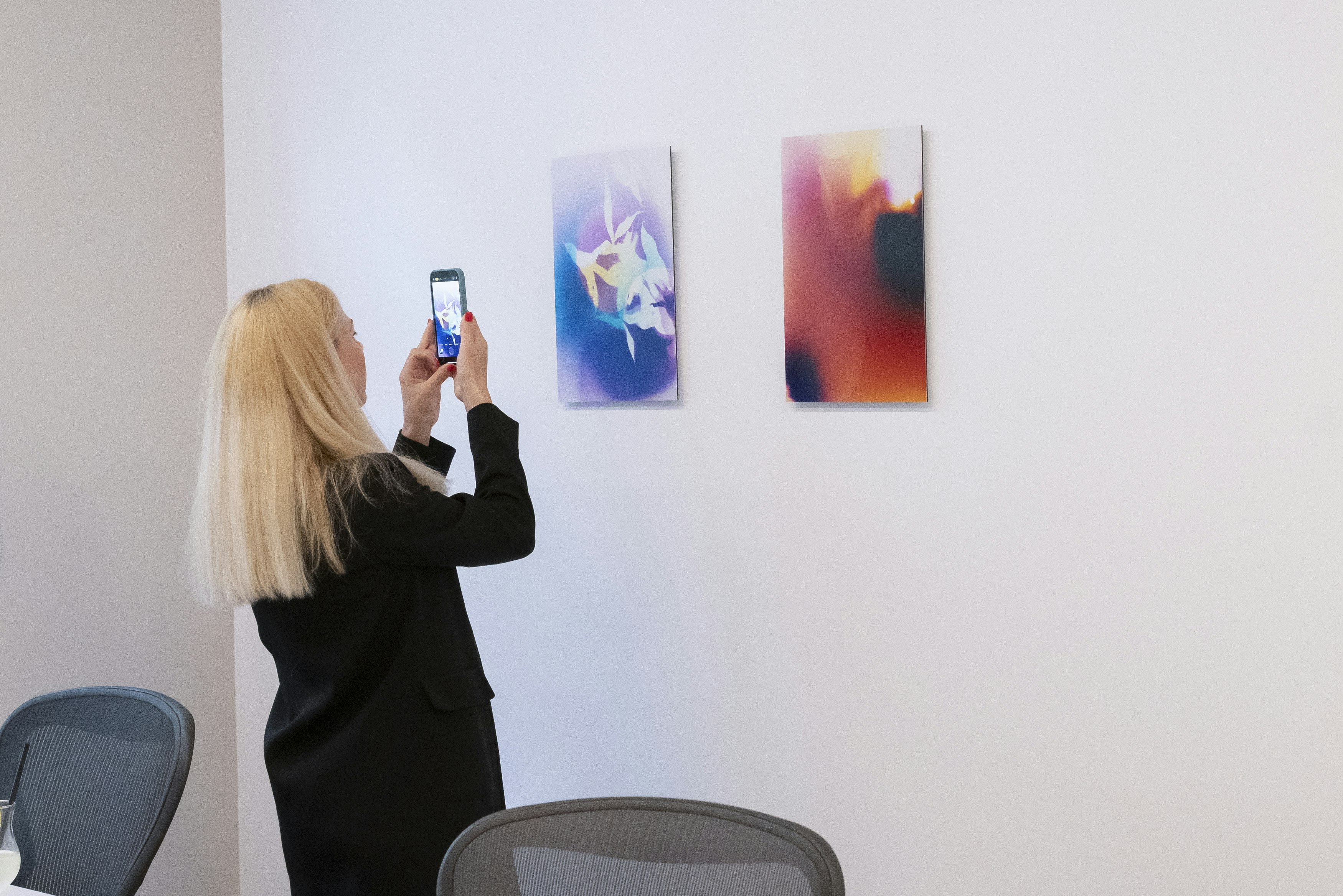 A woman taking picture of art with her phone.