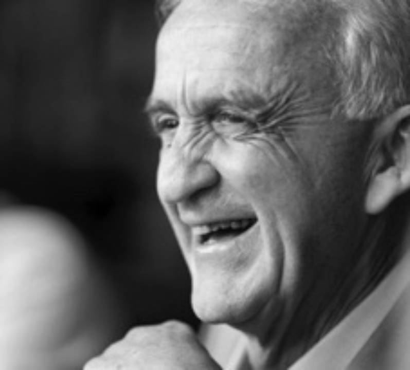 Black and white profile photo of an older man, laughing.