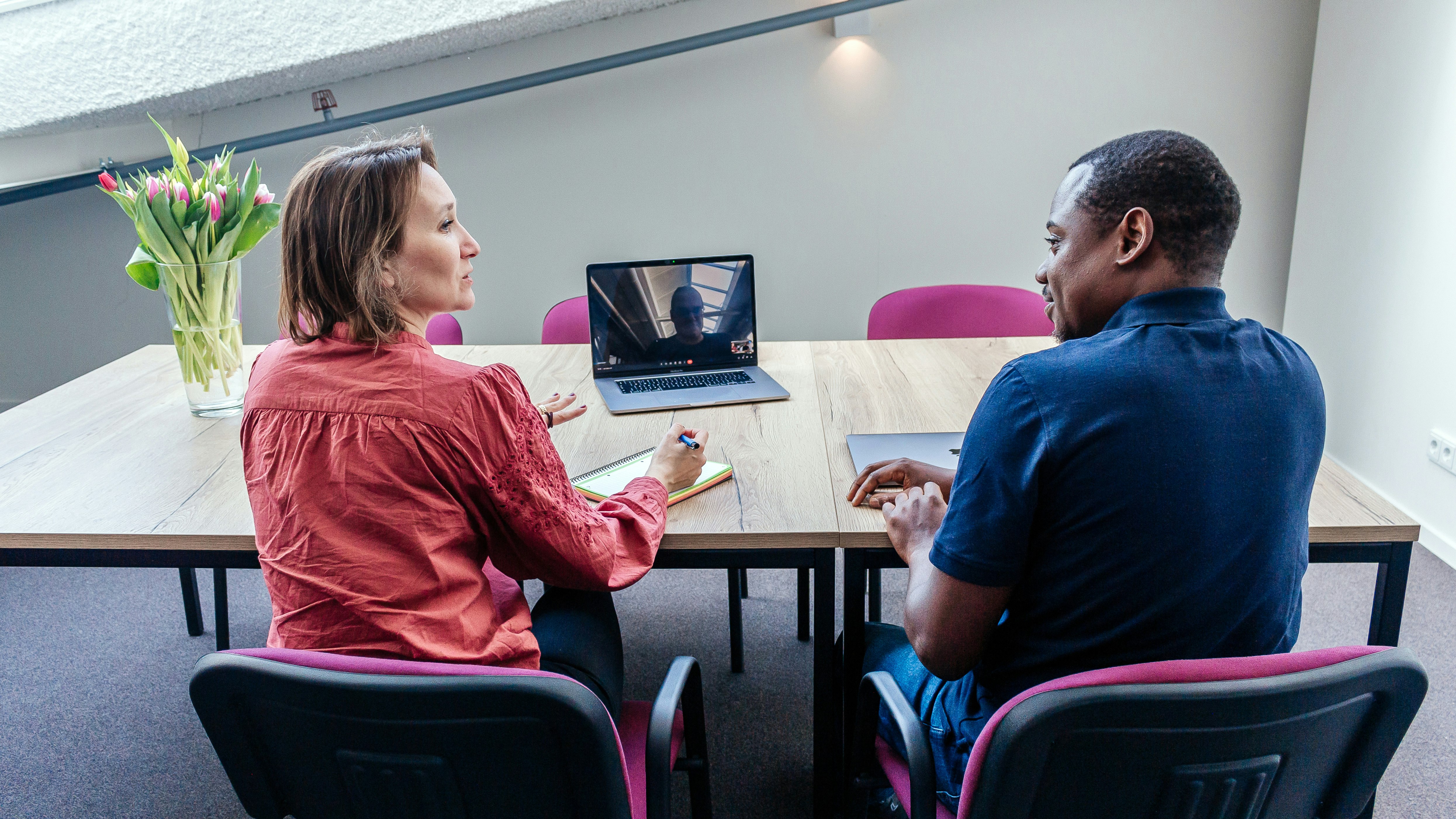 A man and woman in a conversation with a third person on a screen