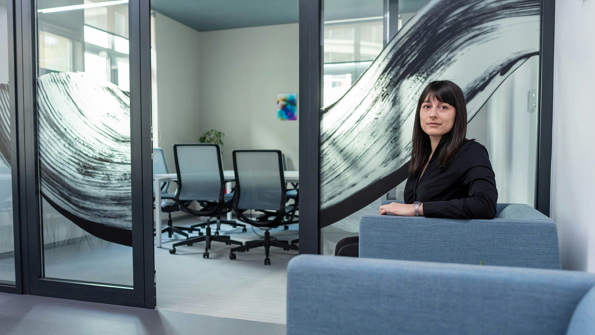 A young woman standing in a modern looking office.