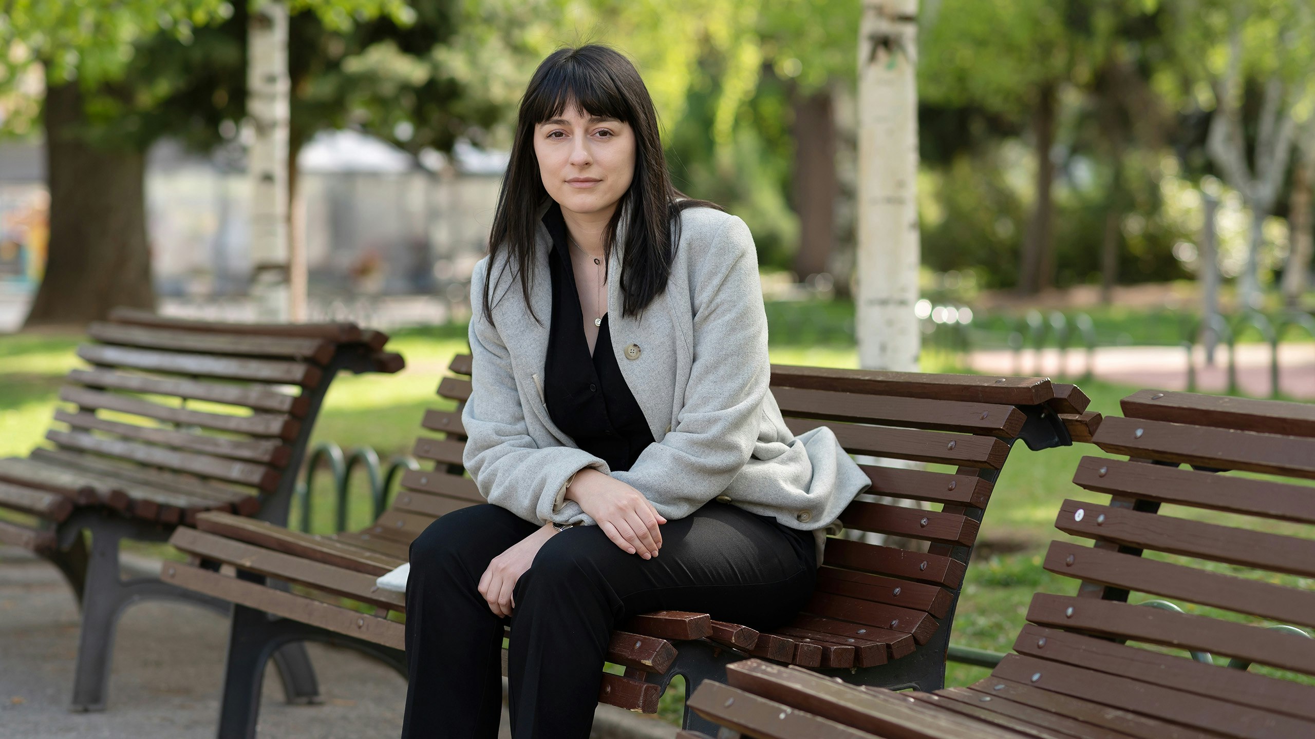 A young woman sitting on a bench in the park.