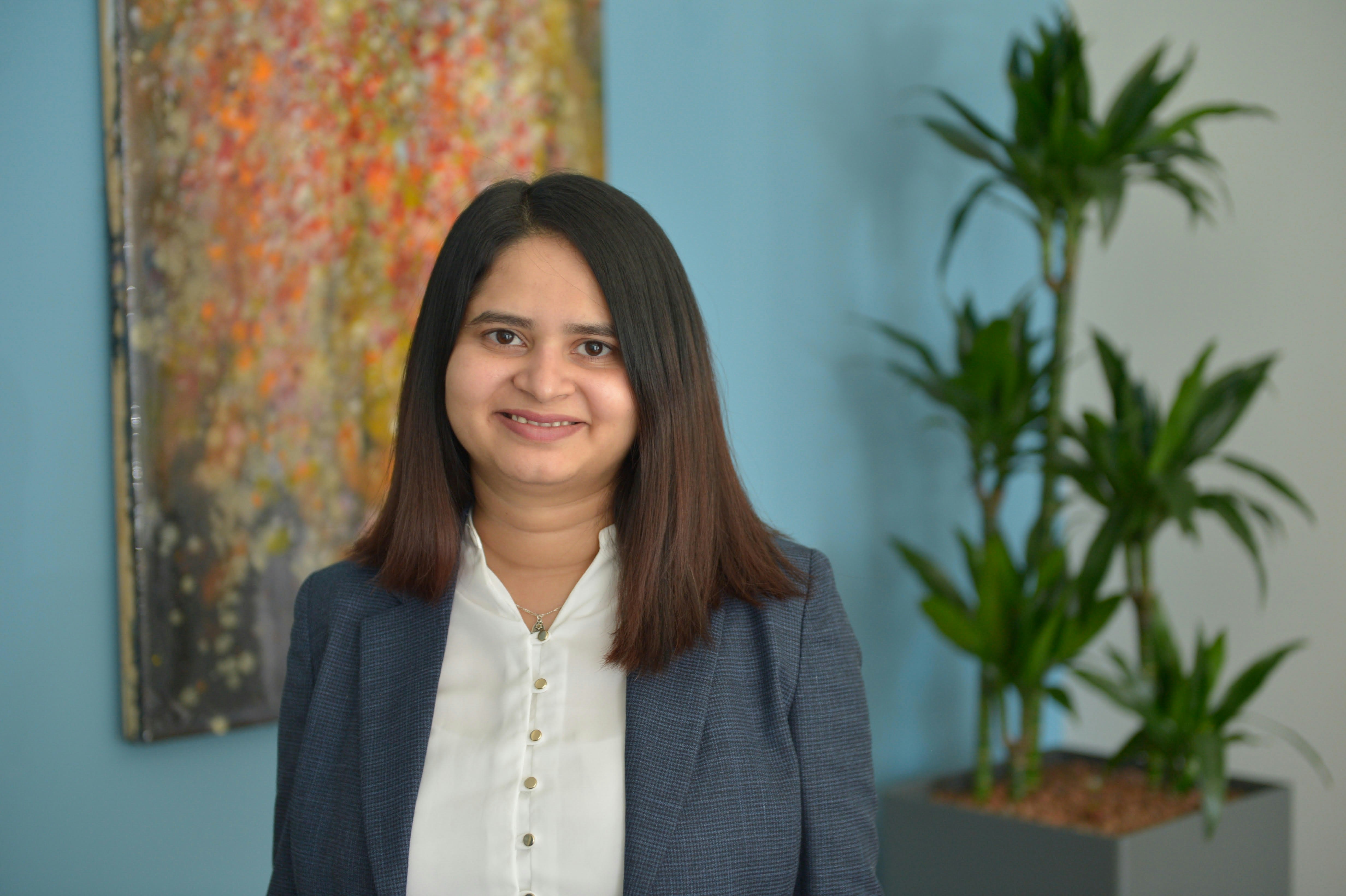 Akshata standing in front of a multicolor-painting