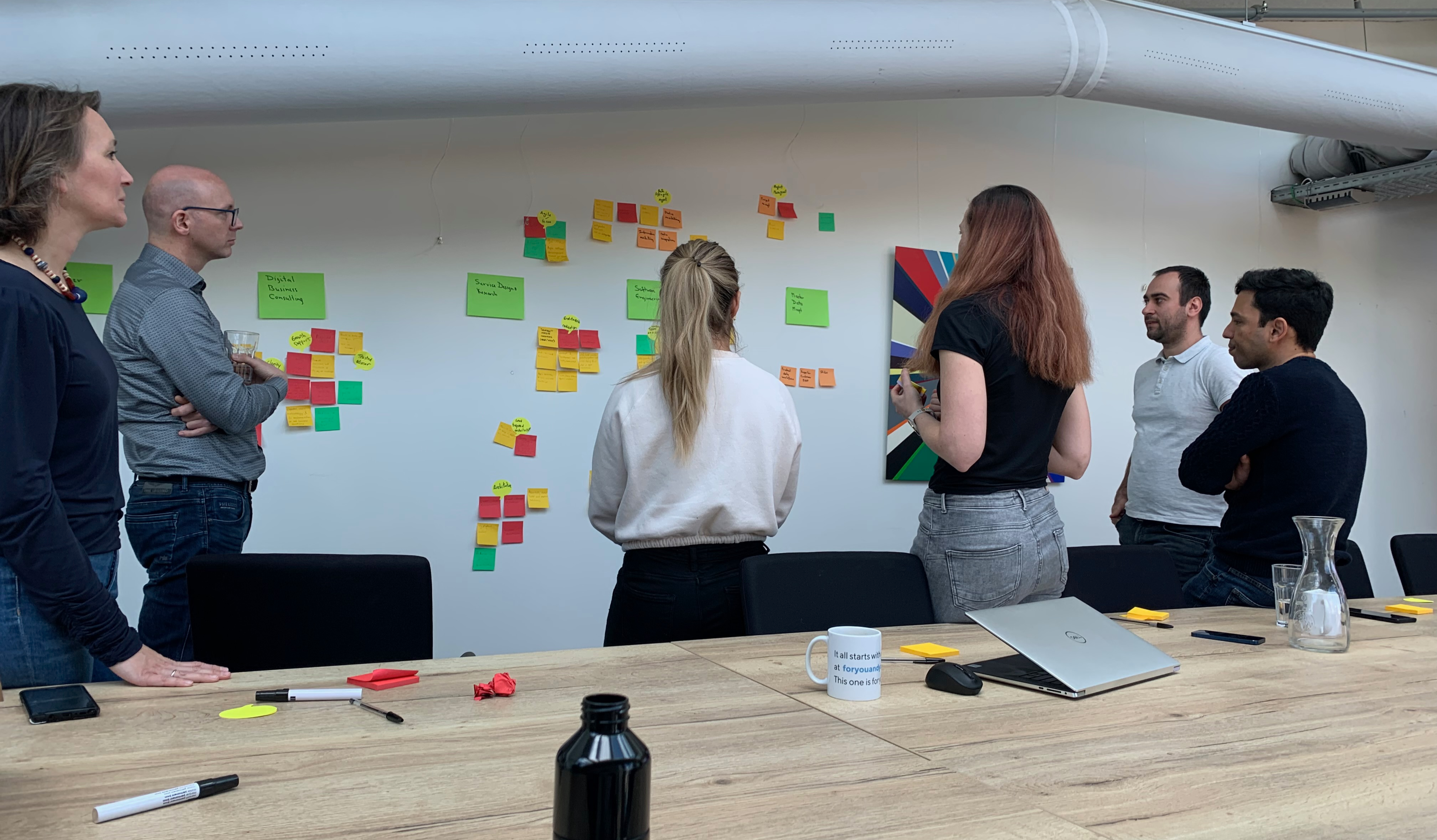 Group of people looking at a wall covered in colouful post-it notes.