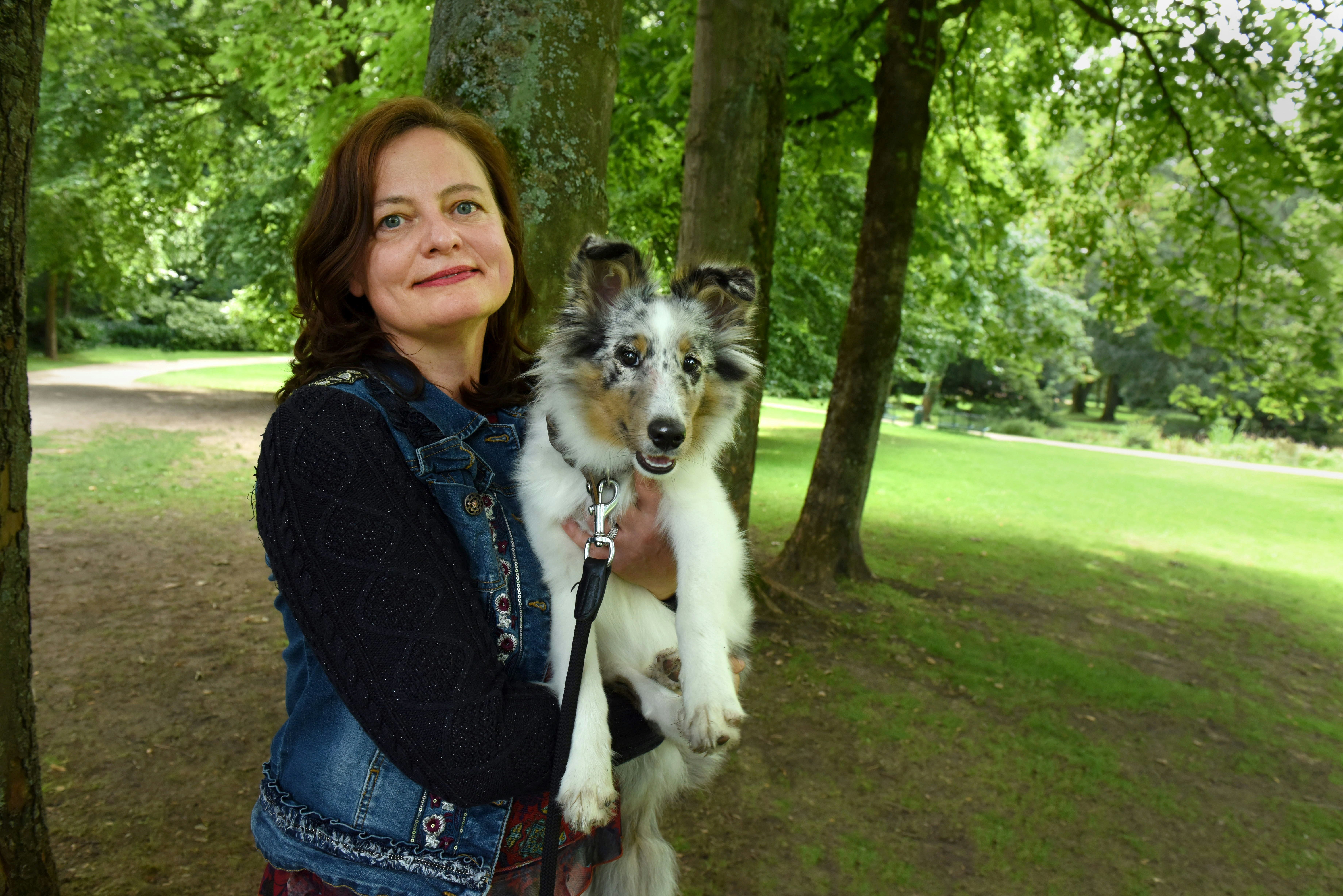 Susanne im park mit ihrem Hund im arm
