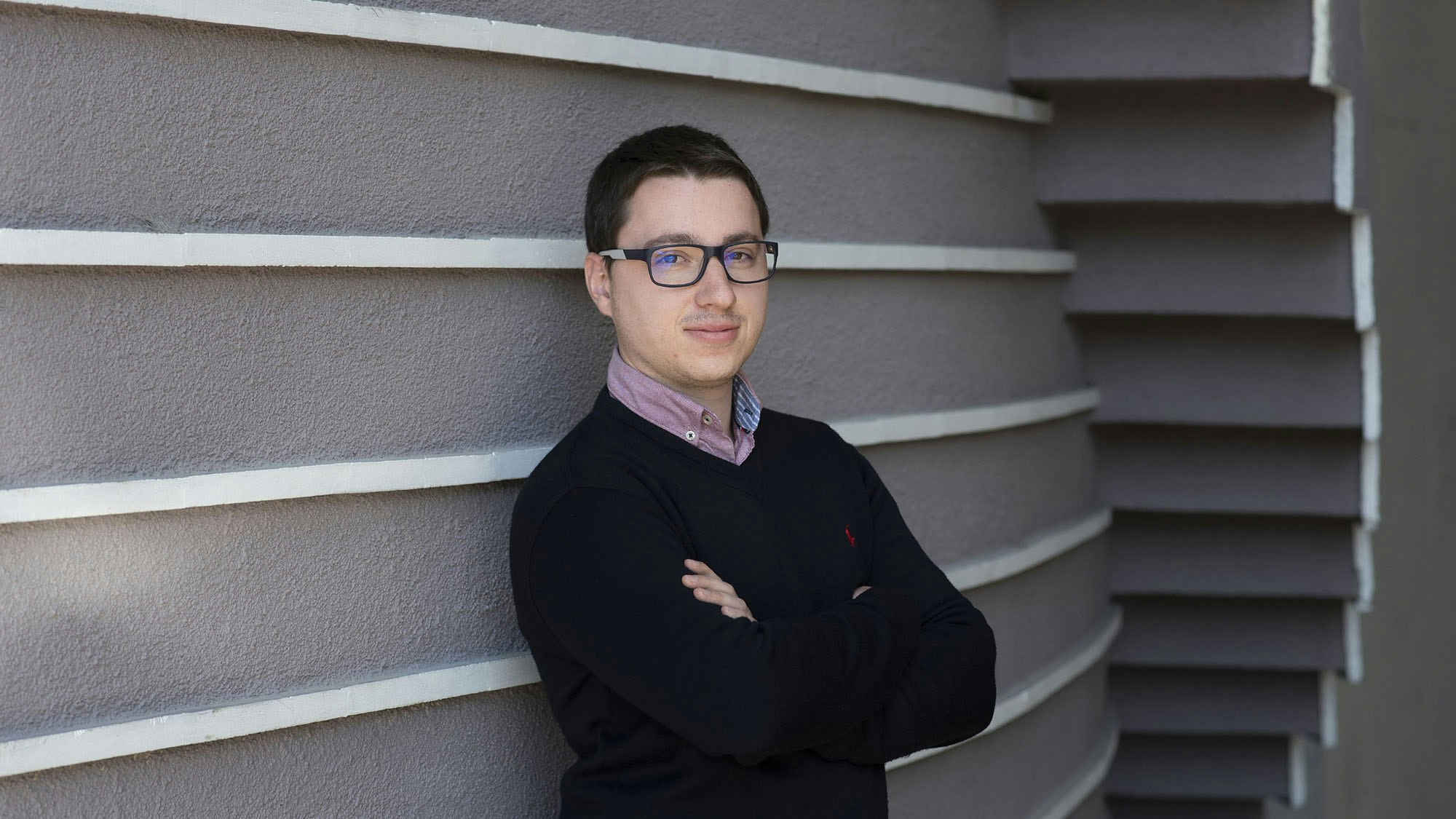 Young man standing next to a wall.