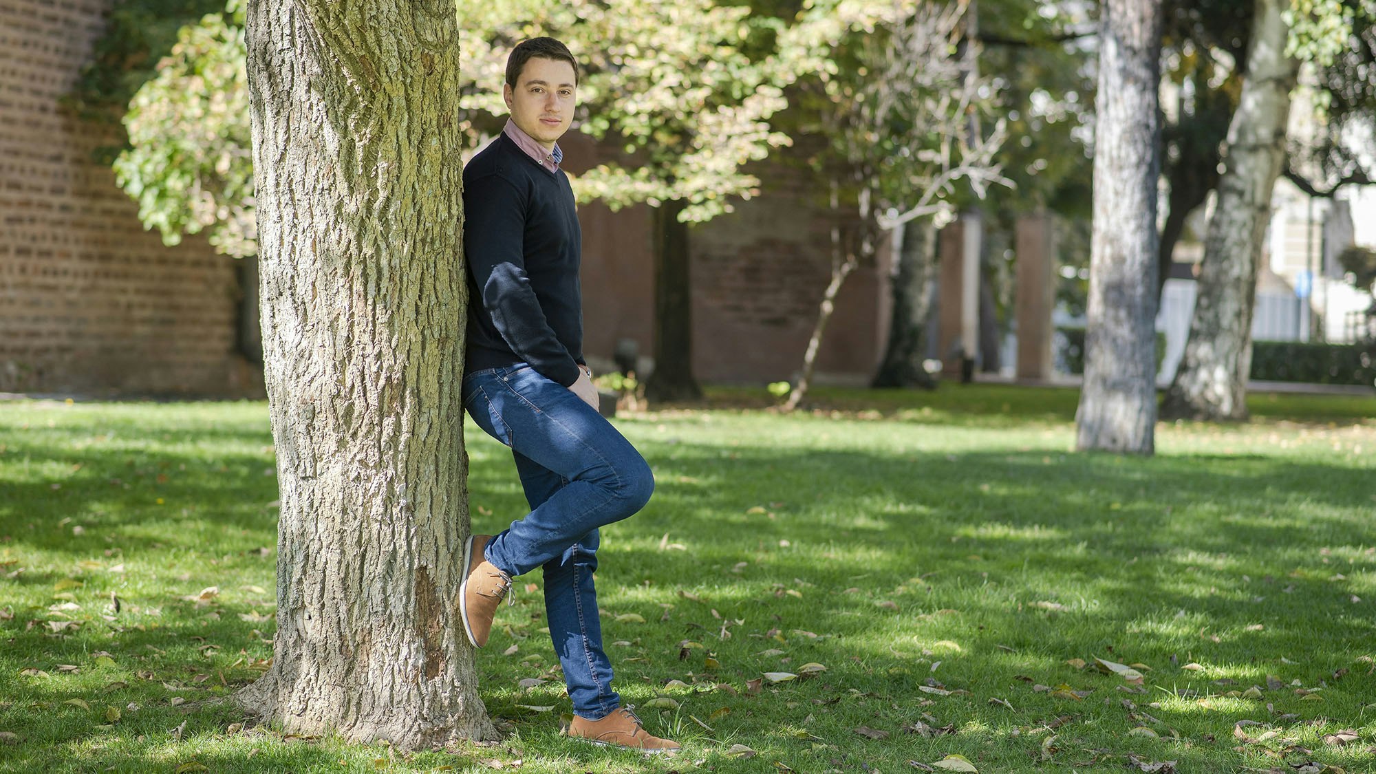 Young man standing next to a tree.