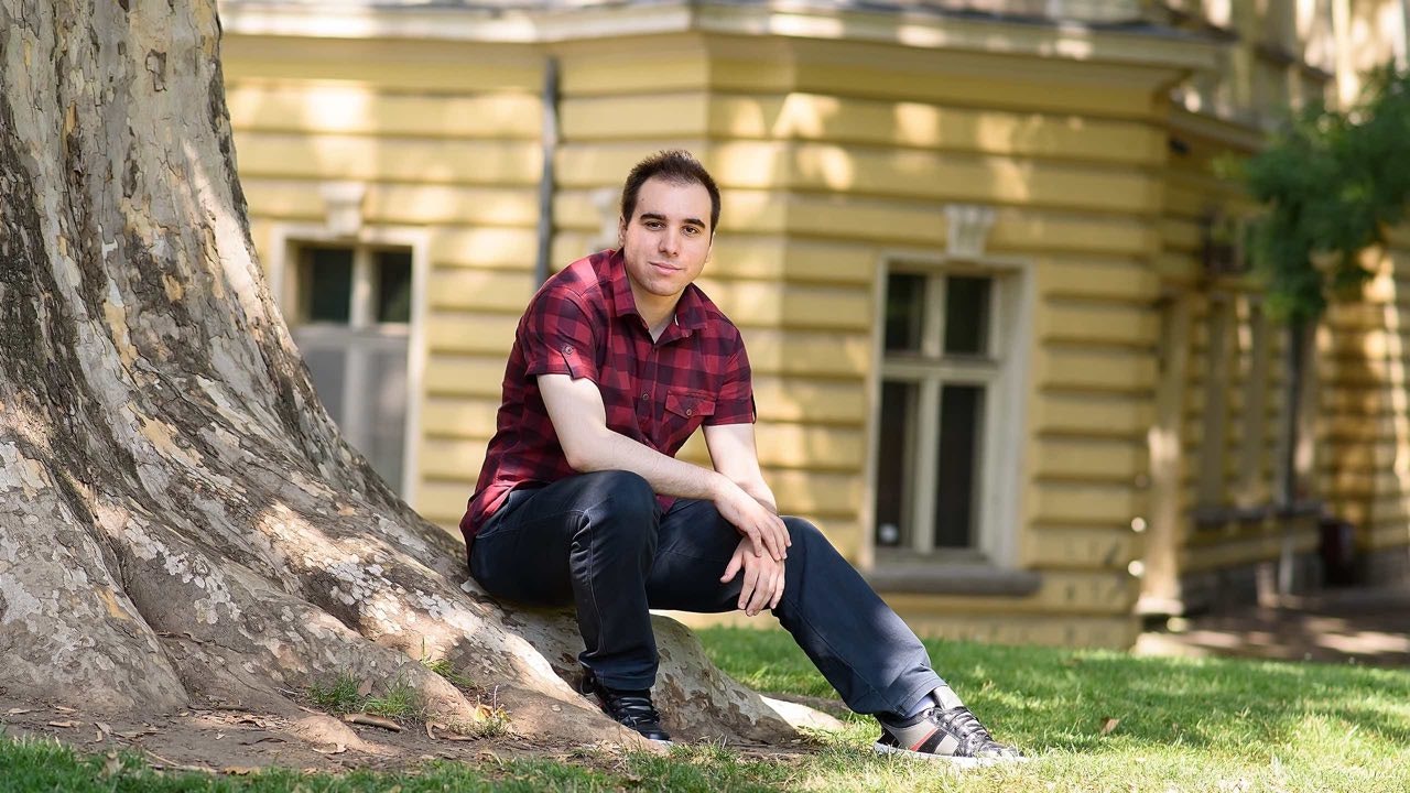 Young man standing next to a tree.