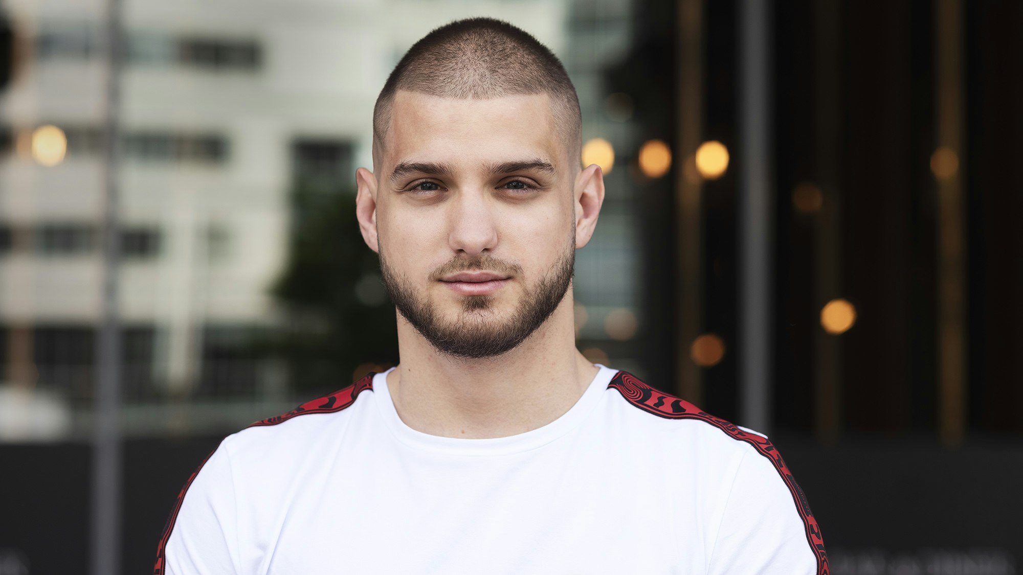 Young man standing before glass wall.